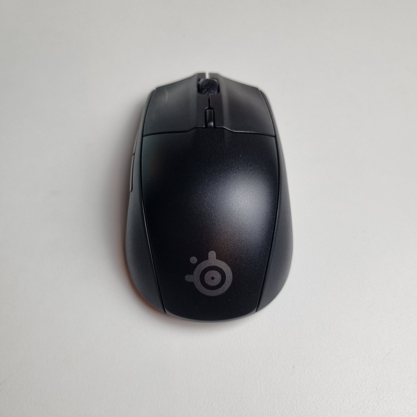 Black SteelSeries Rival 3 wireless refurbished computer mouse with a logo on a light gray background