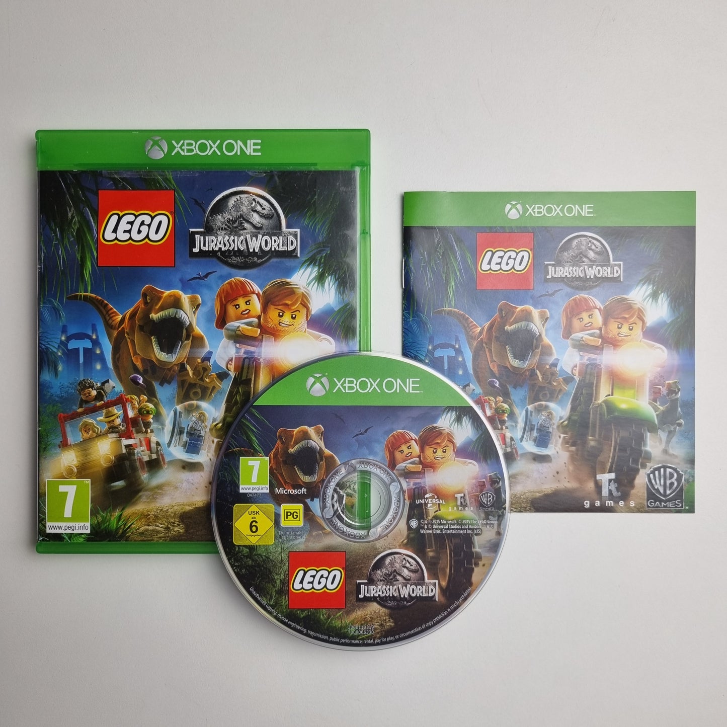 Xbox One game disc, case and insert for 'LEGO Jurassic World' on a grey background