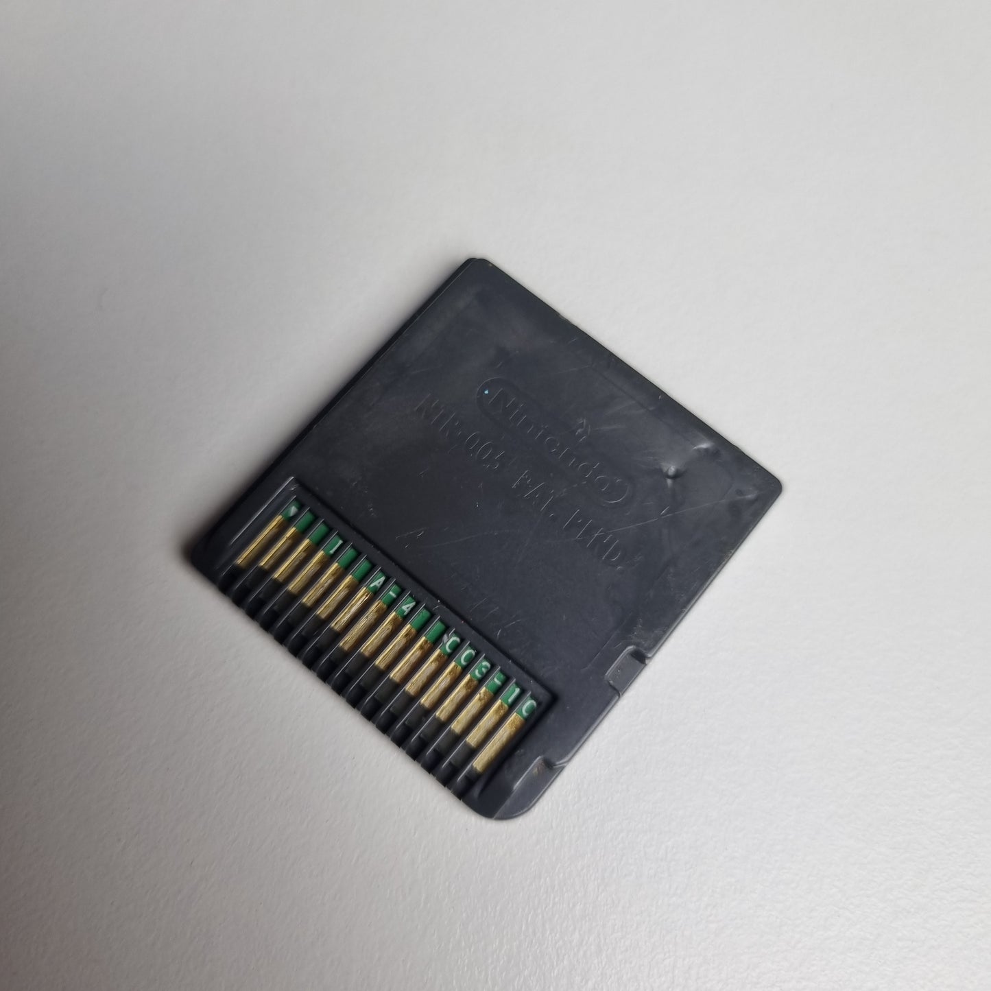 The back of a vide game cartridge for Animal Crossing: Wild World for the Nintendo DS, showing some damage to the cartridge shell. The cartridge is on a white background.