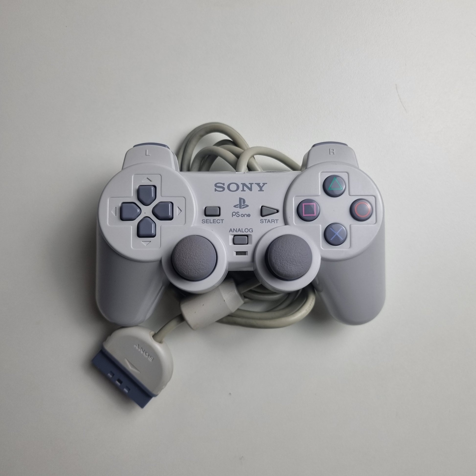 Gray official Sony PlayStation 1  refurbished gaming controller on a light gray background