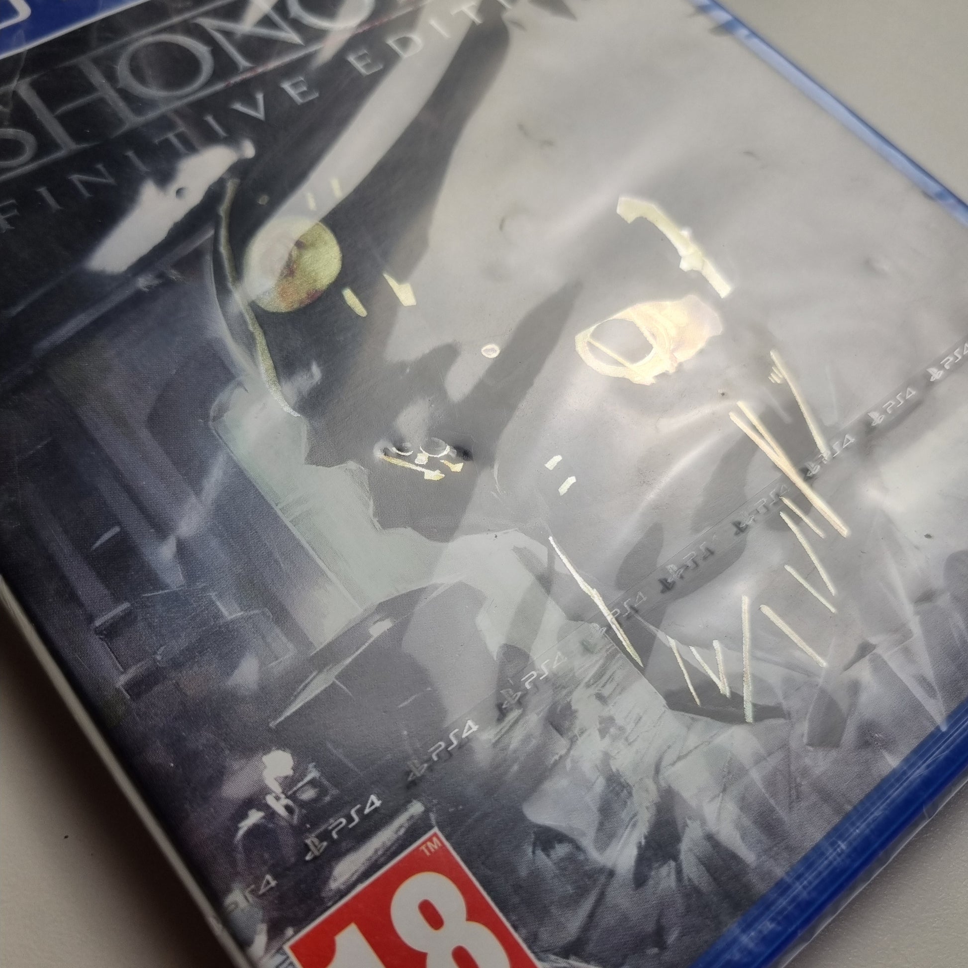 Close-up of a brand new official Sony PlayStation 4 game titled 'Dishonored: Definitive Edition'  on a light gray background