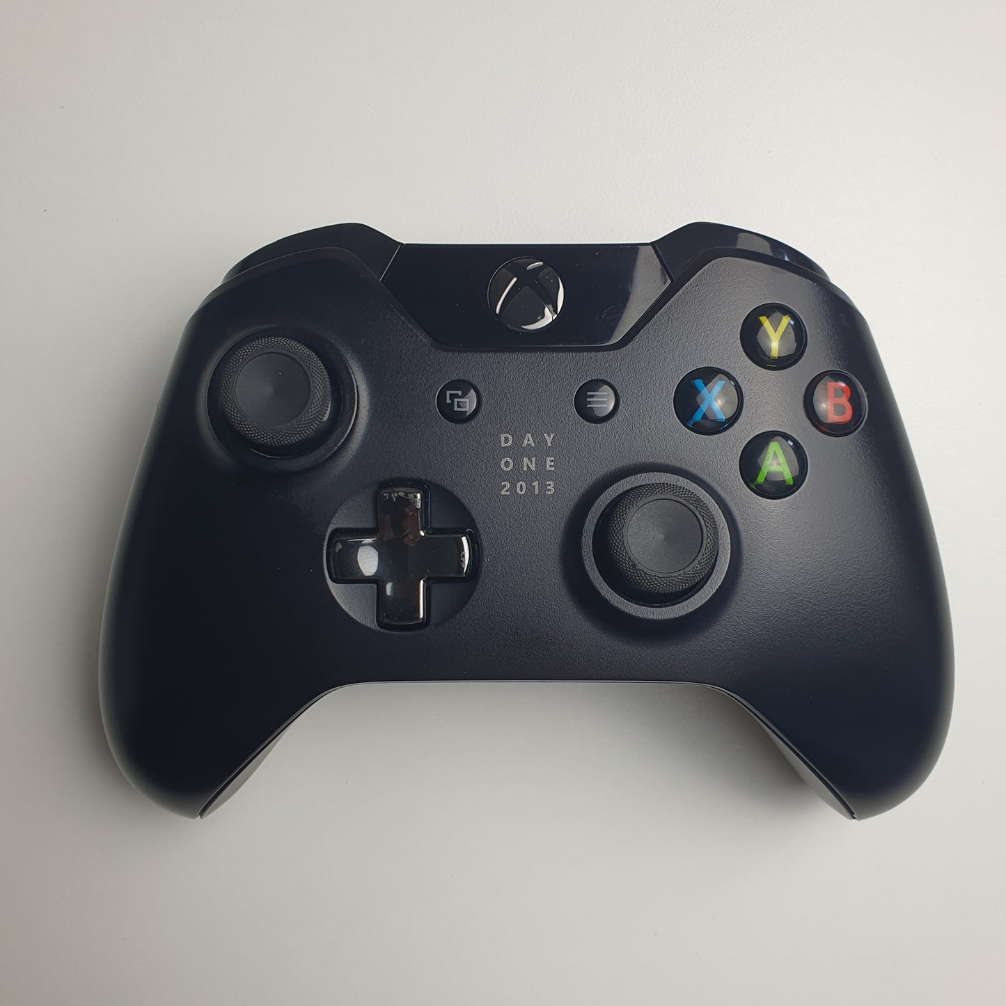 Front of a black 'Day One 2013' Xbox One controller on a white background