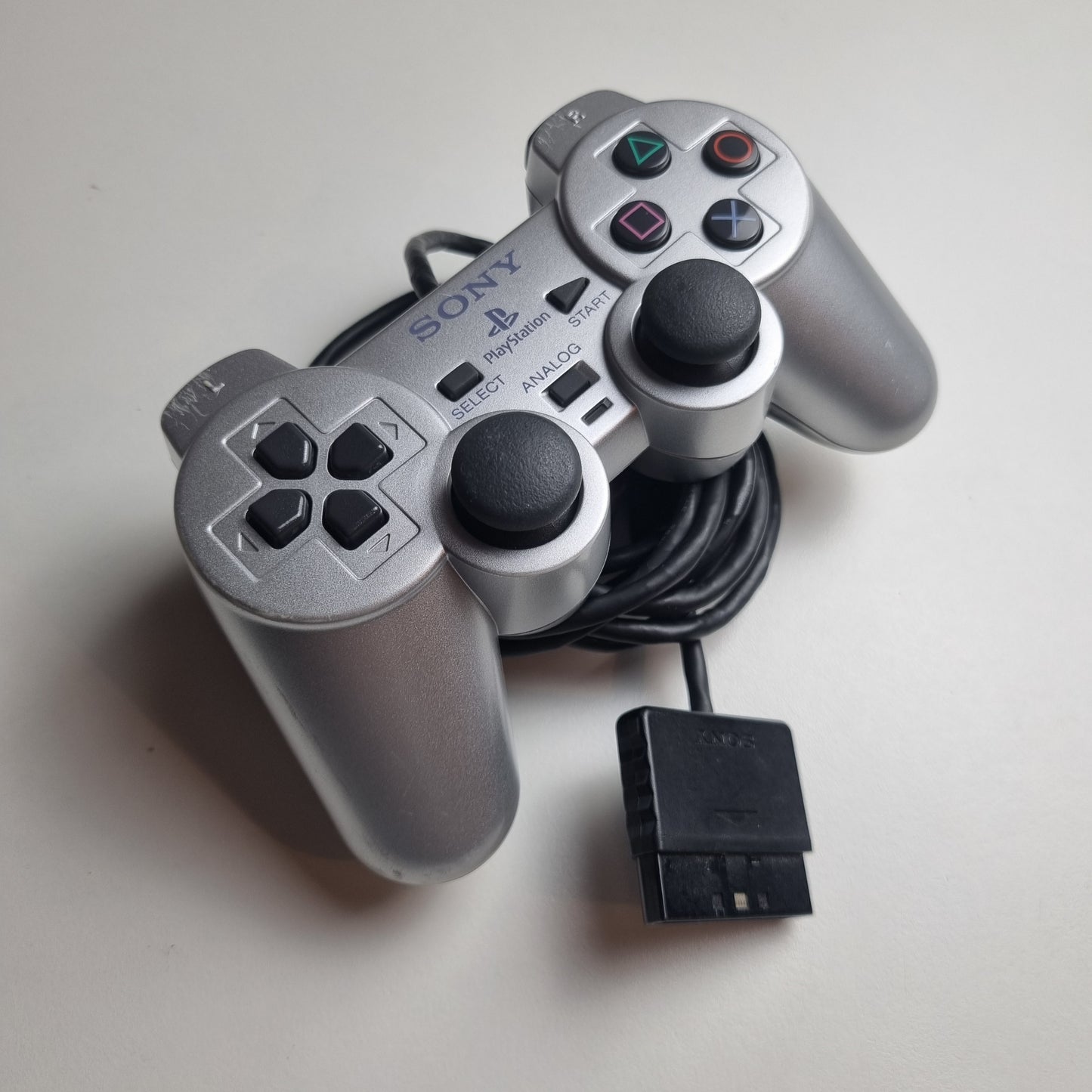 Refurbished official silver Sony PlayStation 2 wired controller, showing signs of wear and tear.