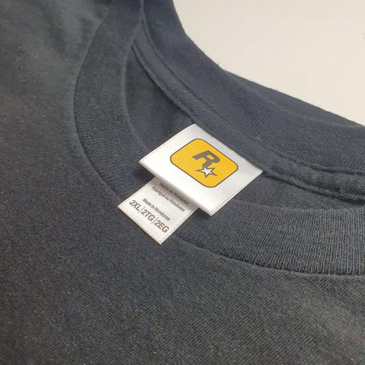 Close-up of a black garment with a label featuring a Rockstar logo on a grey background