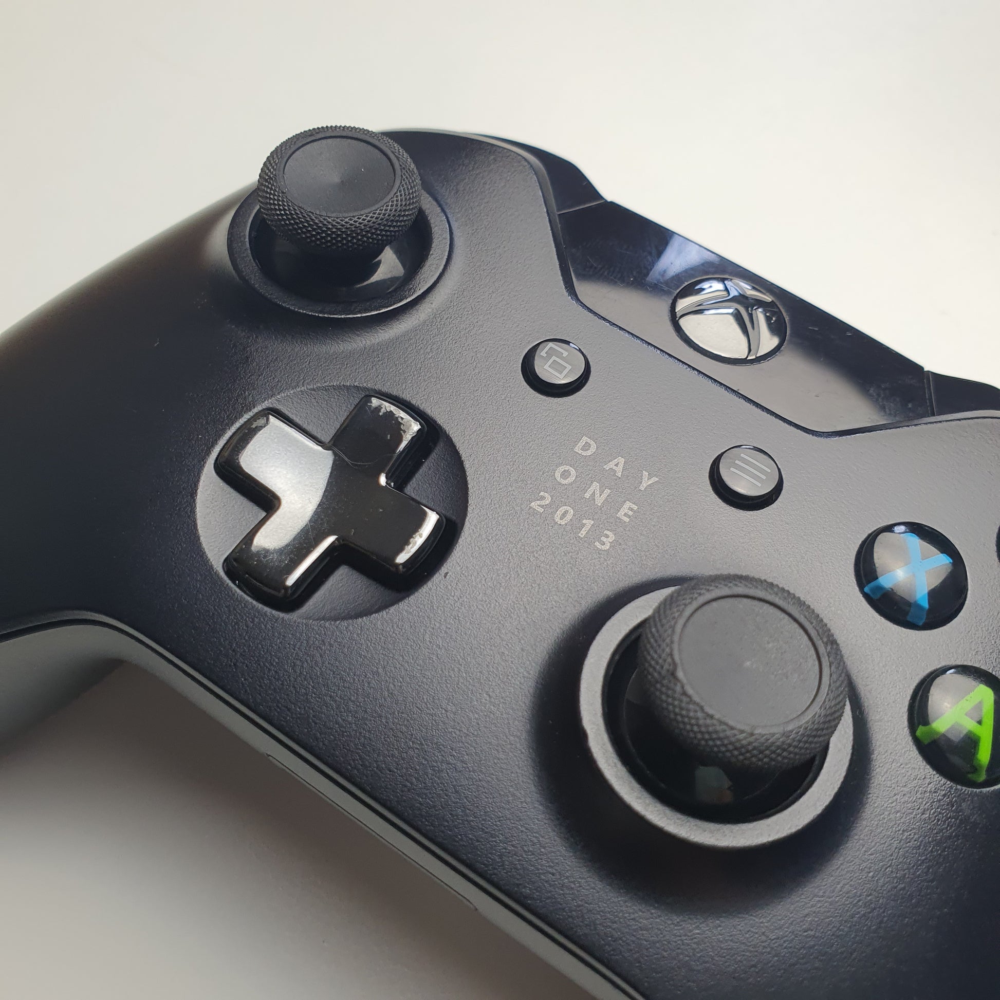 Close-up of a Xbox One controller with 'Day One 2013' visible on a light grey background
