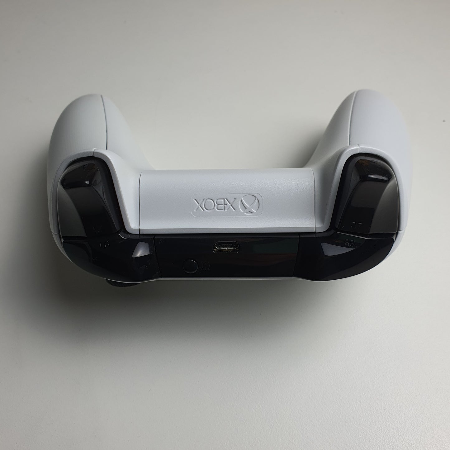 Top of a white Xbox One controller on a light grey background
