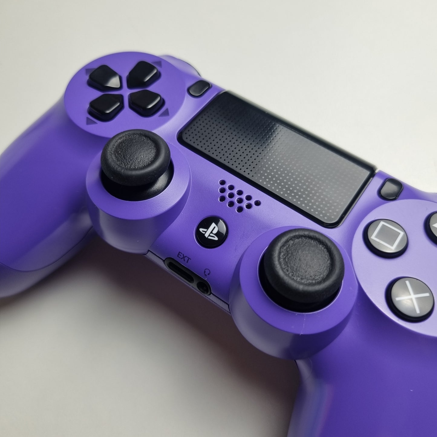 Electric purple official Sony PlayStation DualShock 4 refurbished gaming controller on a light gray background