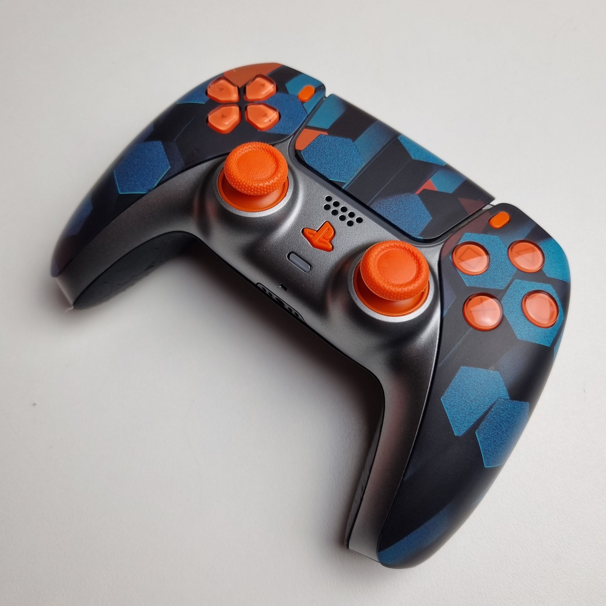 Angled picture of a custom orange, teal & black Sony PlayStation 5 PS5 wireless DualSense controller built by Dogghead Tech on a white background.