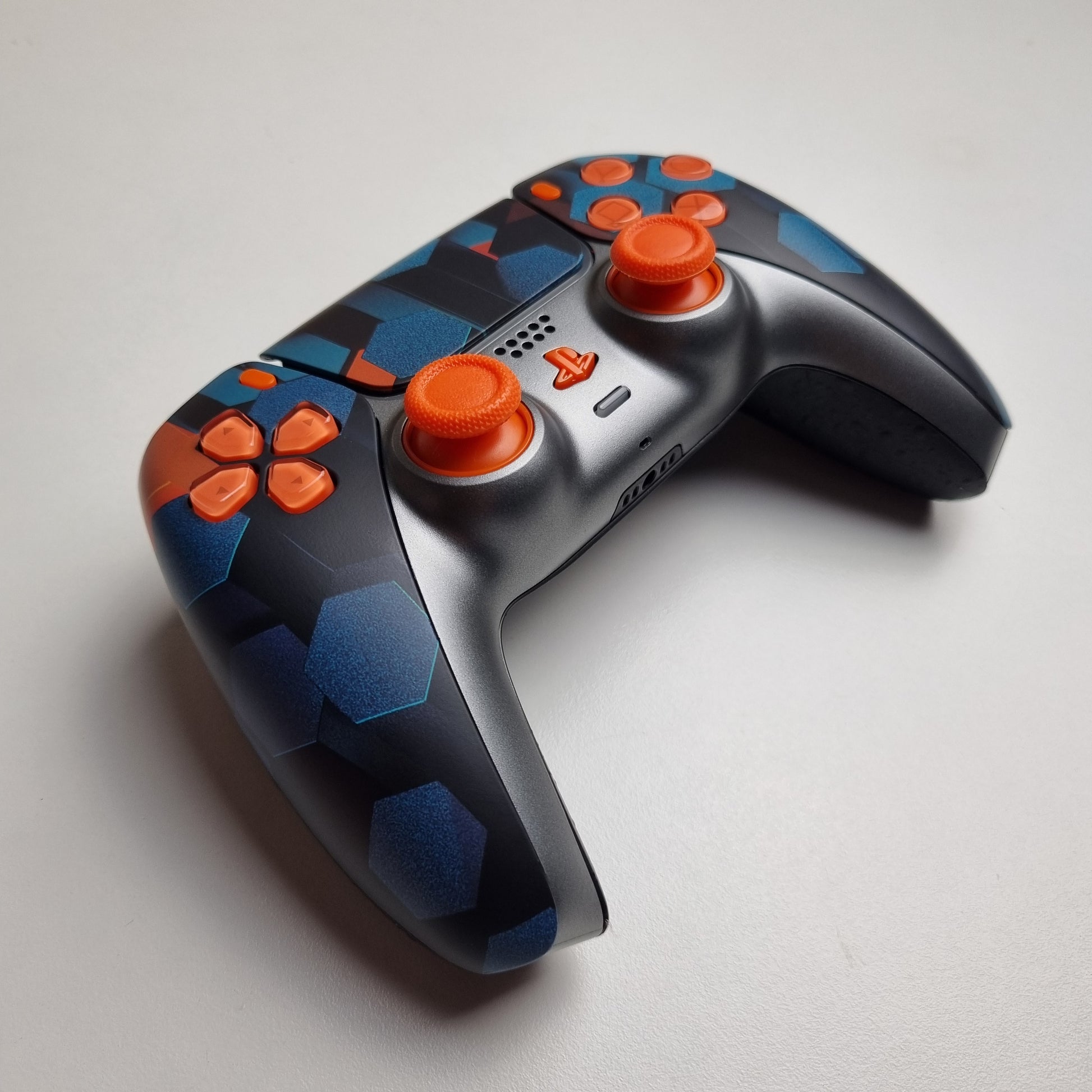 Angled picture of a custom orange, teal & black Sony PlayStation 5 PS5 wireless DualSense controller built by Dogghead Tech on a white background.