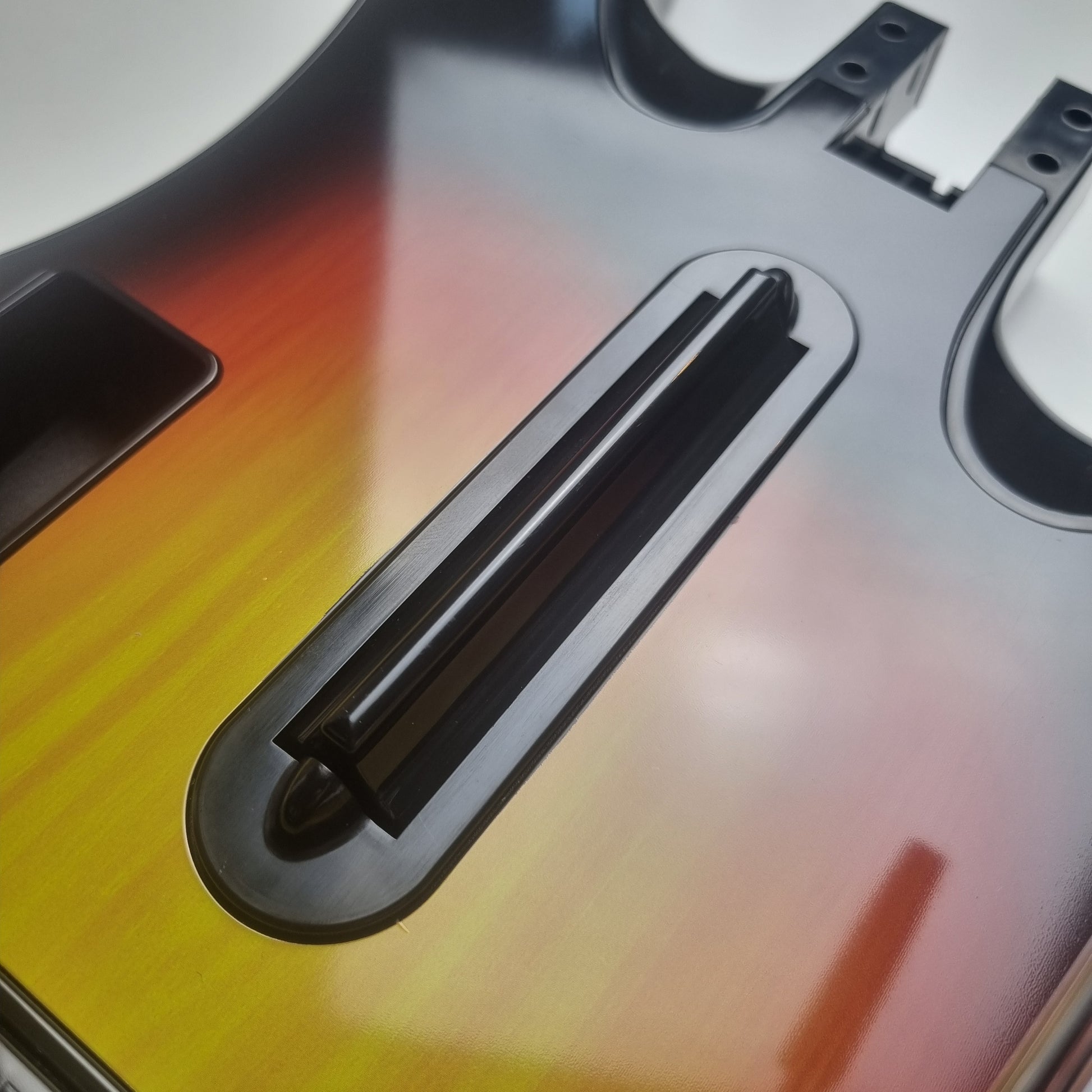 Close-up of the strum button on a official RedOctane Nintendo Wii sunburst guitar controller on a white background.