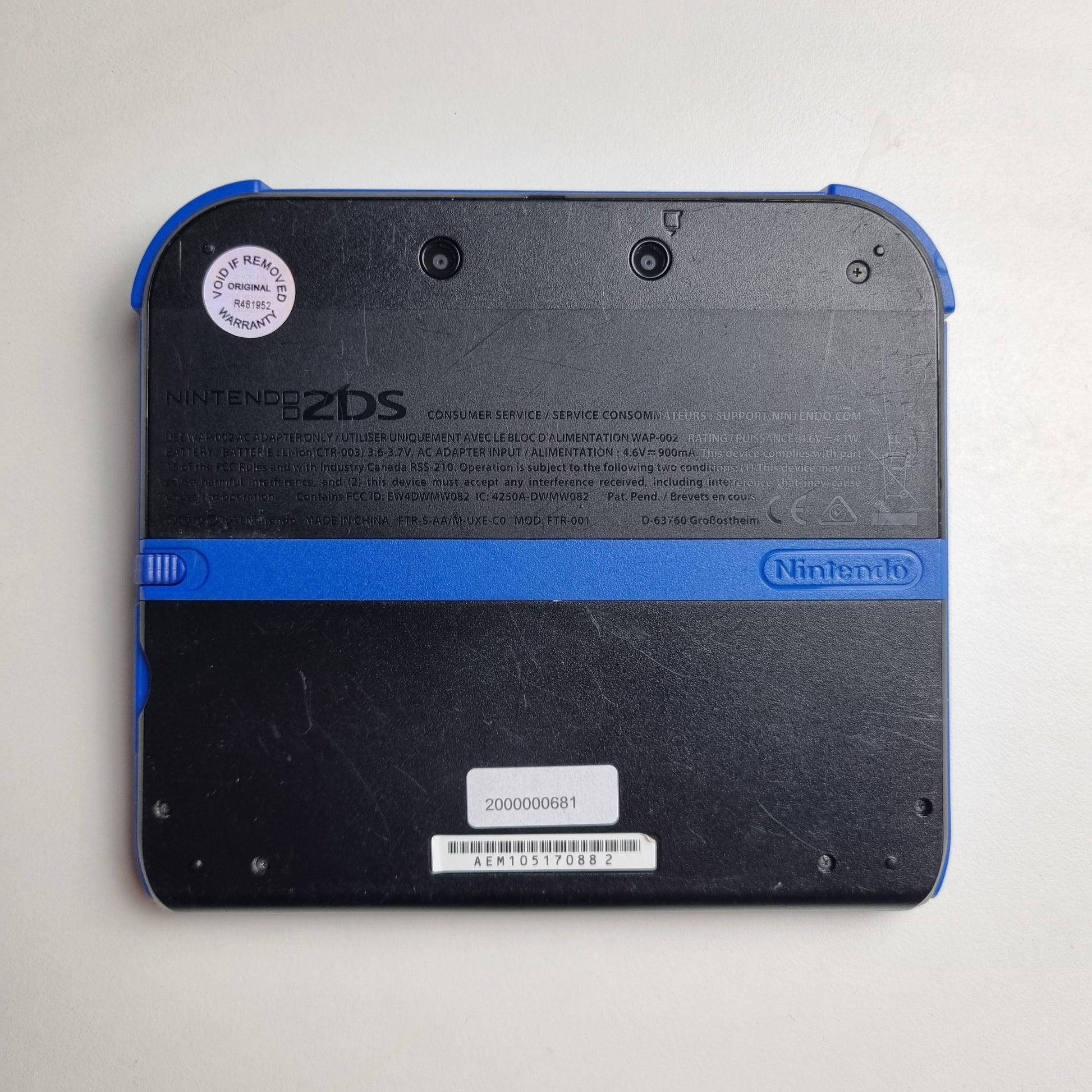 Back of a refurbished Nintendo 2DS black & blue handheld gaming console on a light grey background