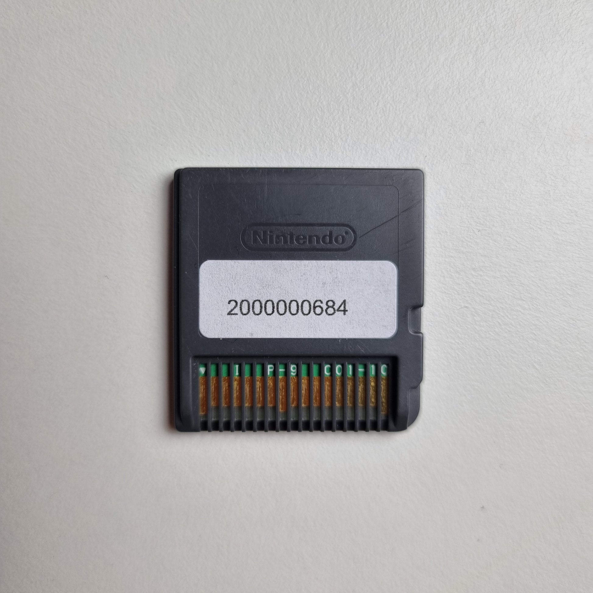 Back of a Nintendo DS game cartridge showing an asset tag, on a light grey background