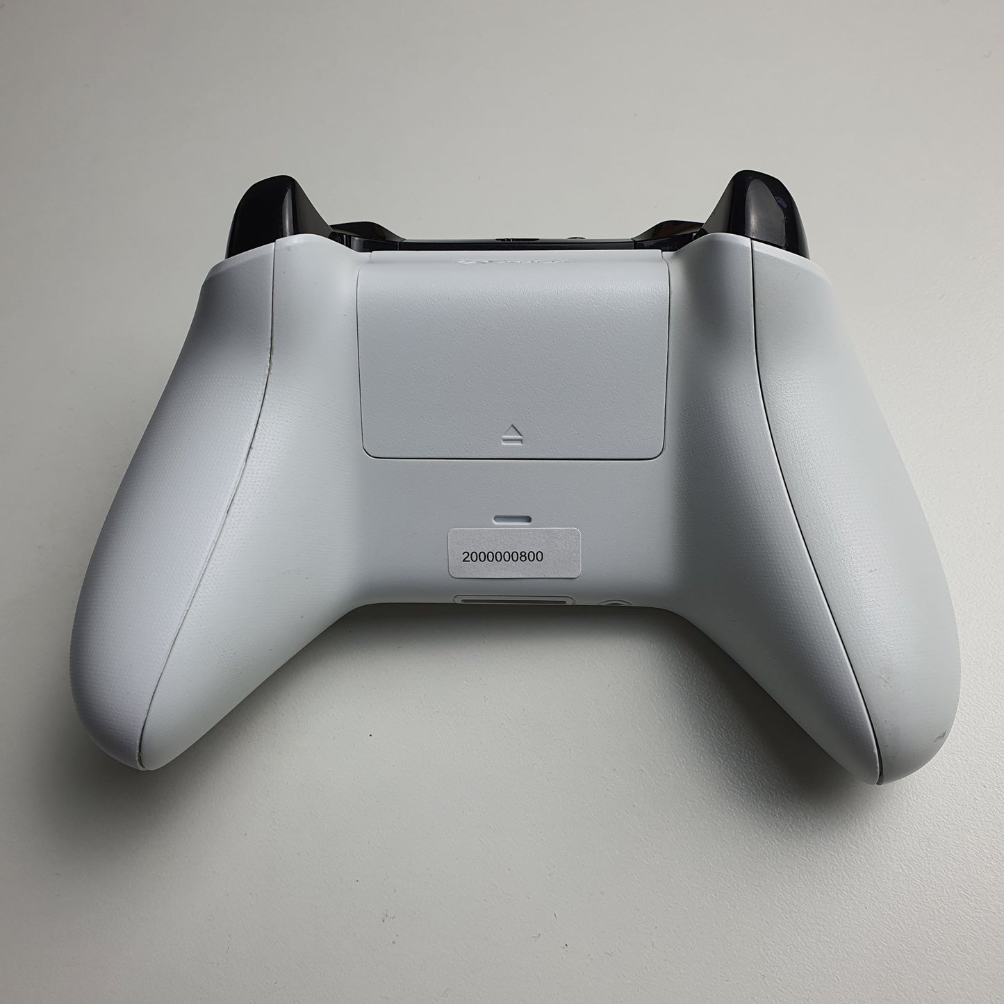 The back of a white Xbox One controller on a light grey background