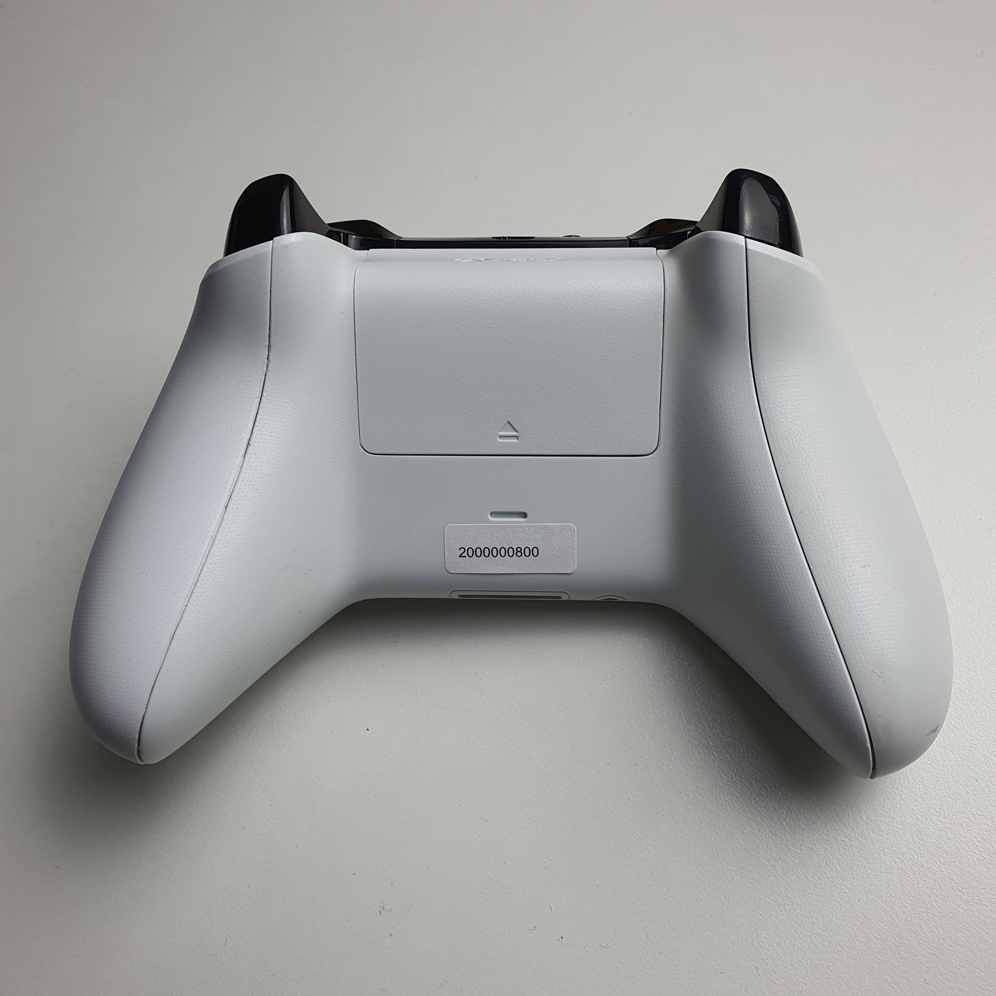 The back of a white Xbox One controller on a light grey background