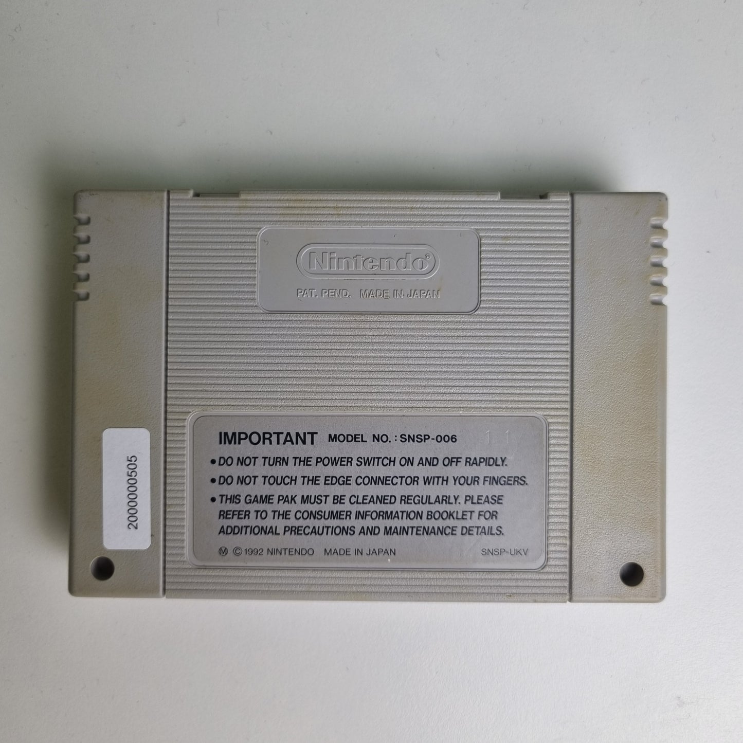 Back of a Super Nintendo game cartridge on a light grey background