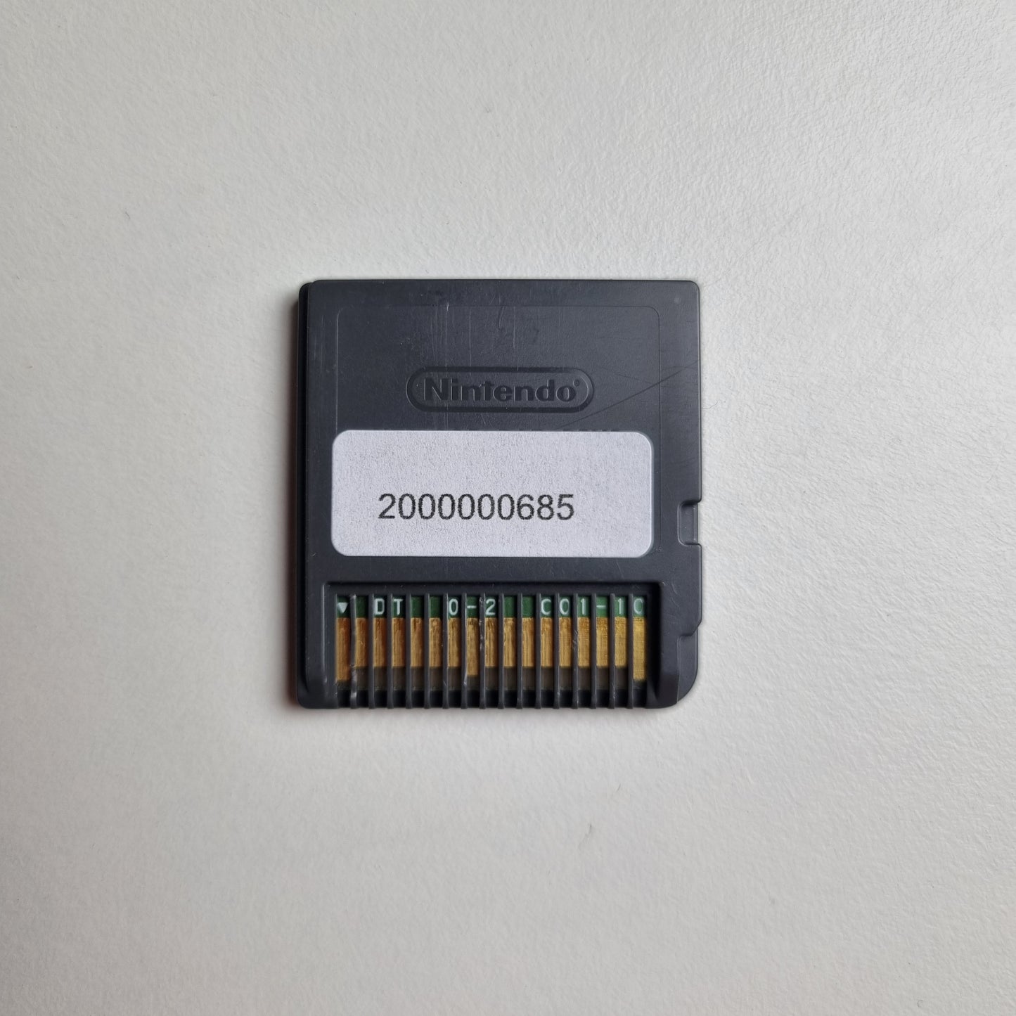 Back of a Nintendo DS game cartridge showing an asset tag, on a light grey background