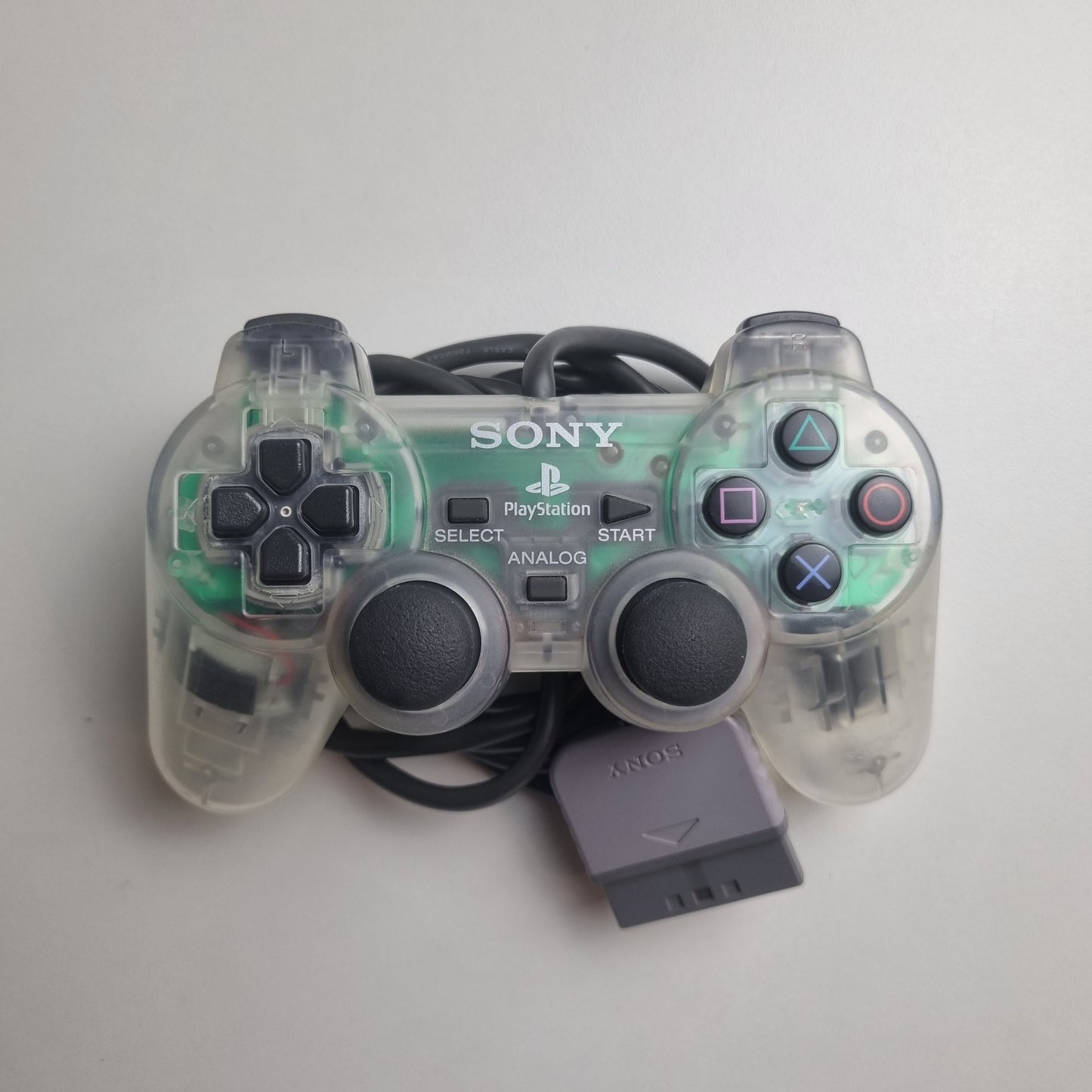 Clear official Sony PlayStation 1 refurbished gaming controller on a light gray background 