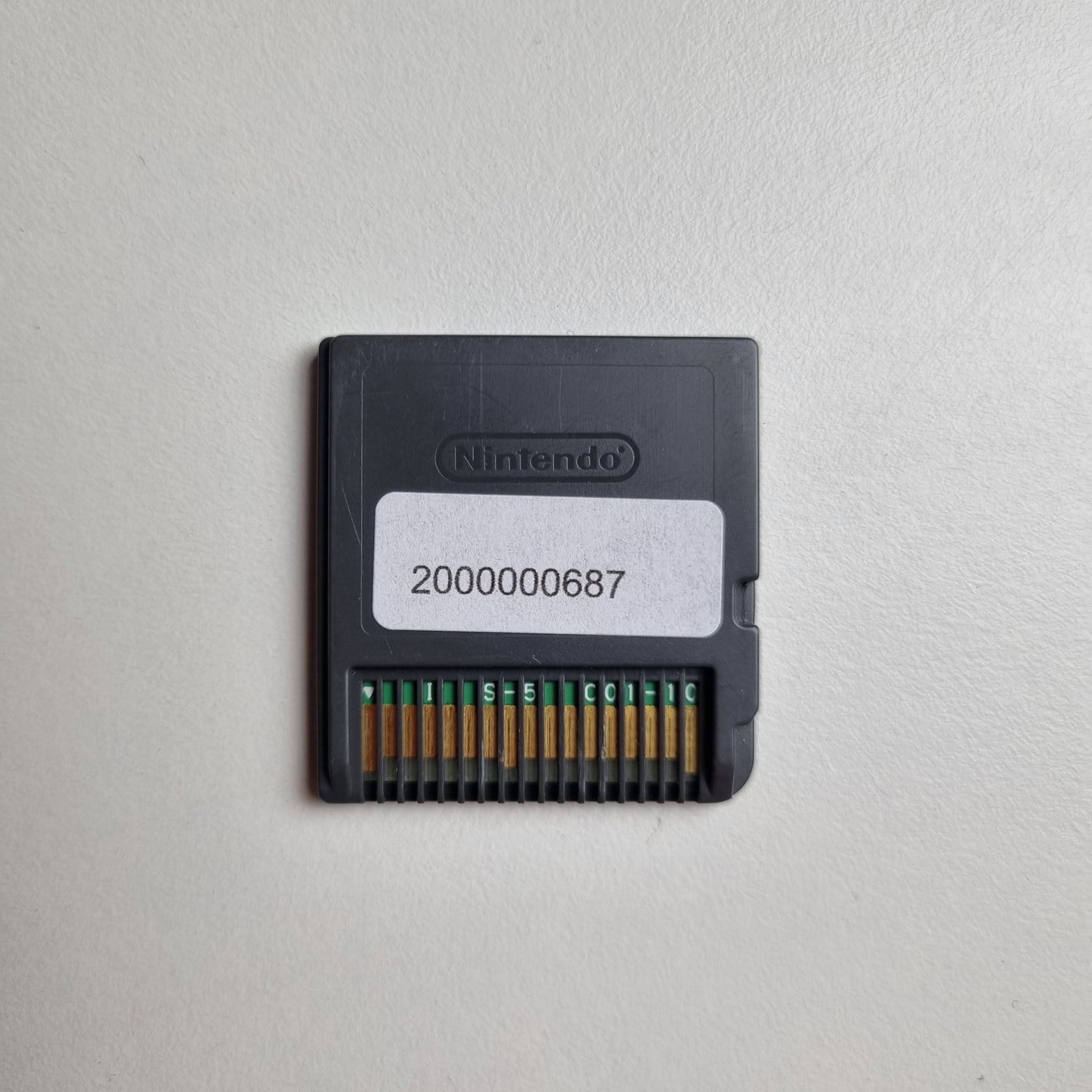 Back of a Nintendo DS game cartridge showing an asset tag, on a light grey background