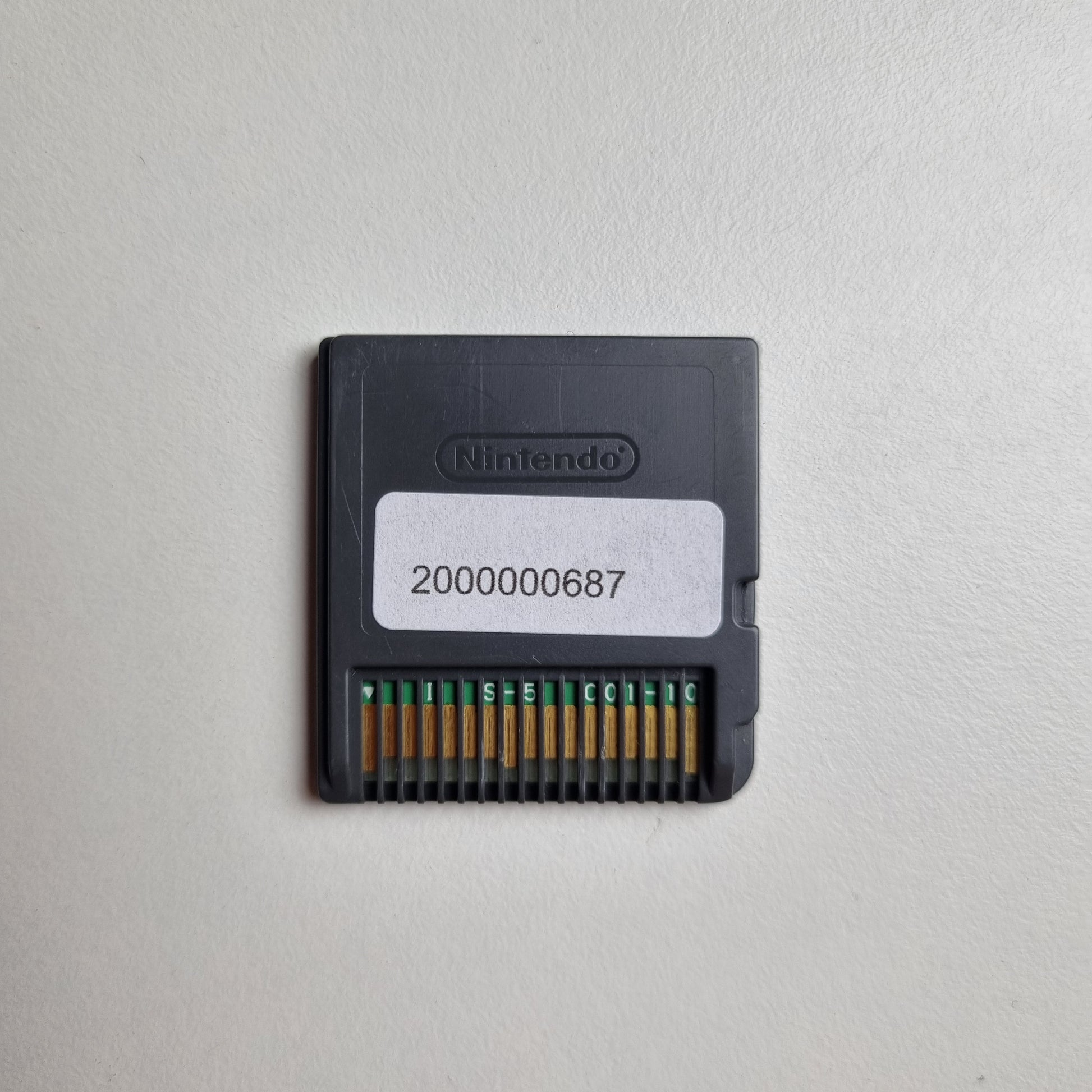 Back of a Nintendo DS game cartridge showing an asset tag, on a light grey background