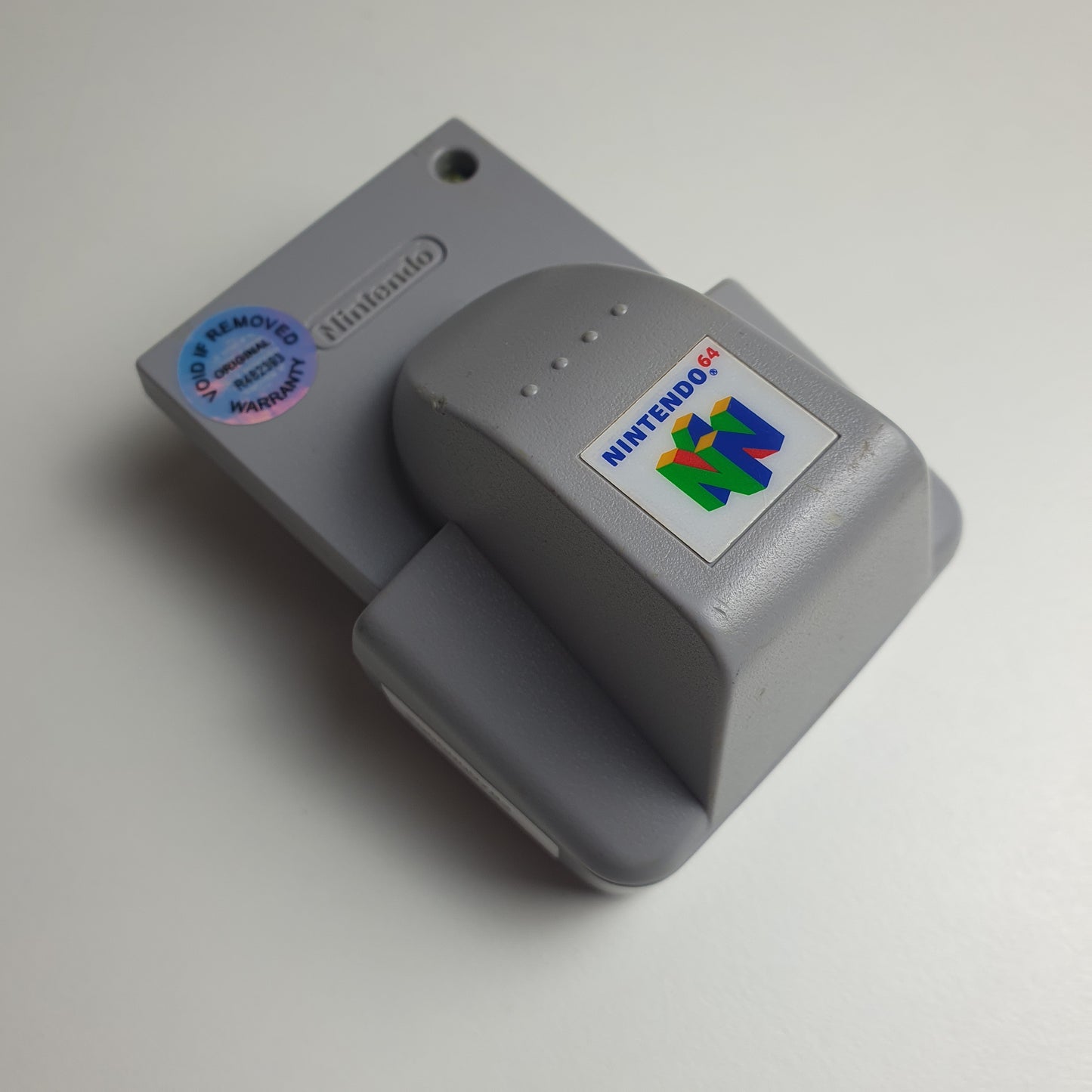 Grey Nintendo 64 N64 rumble pak on a white background 