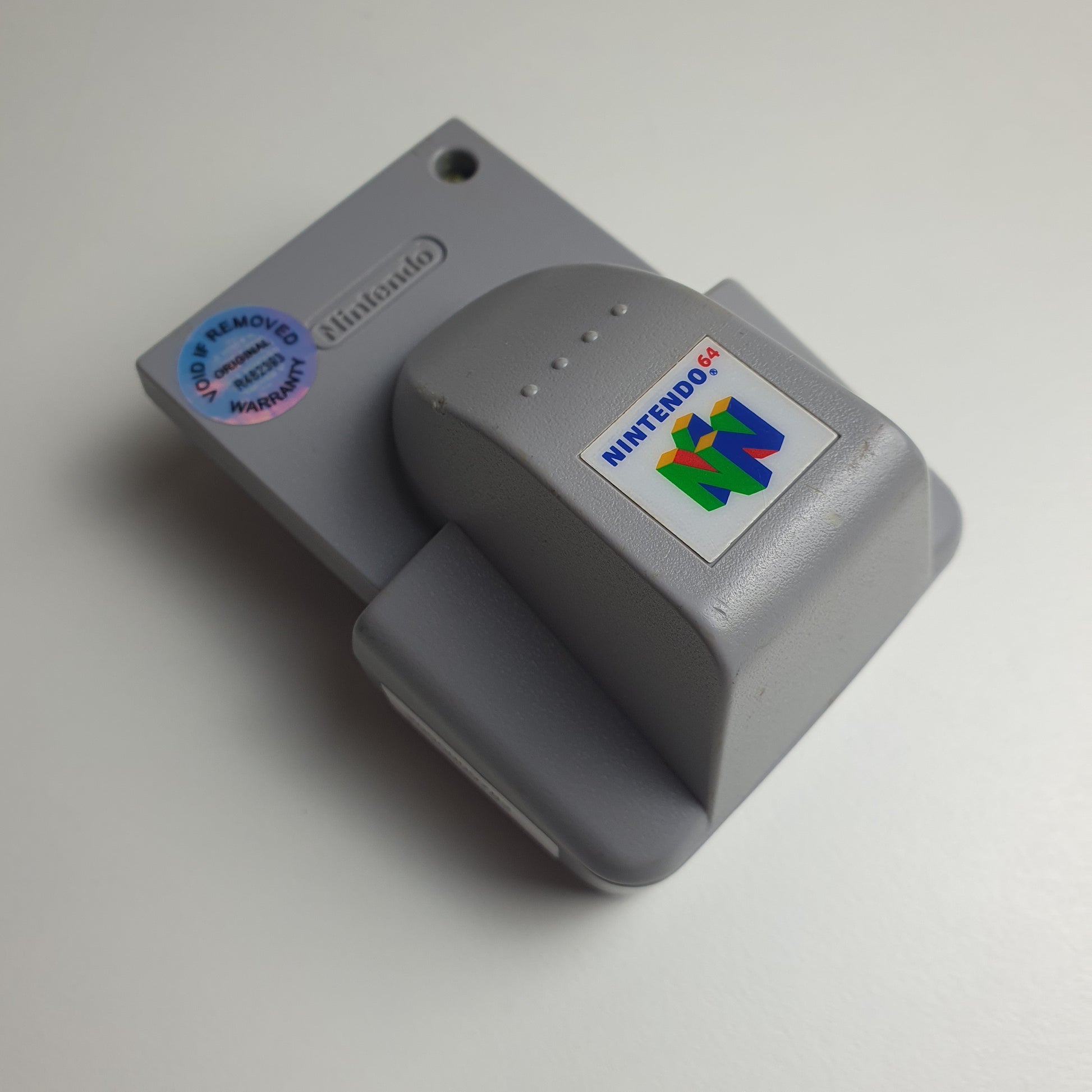 Grey Nintendo 64 N64 rumble pak on a white background 