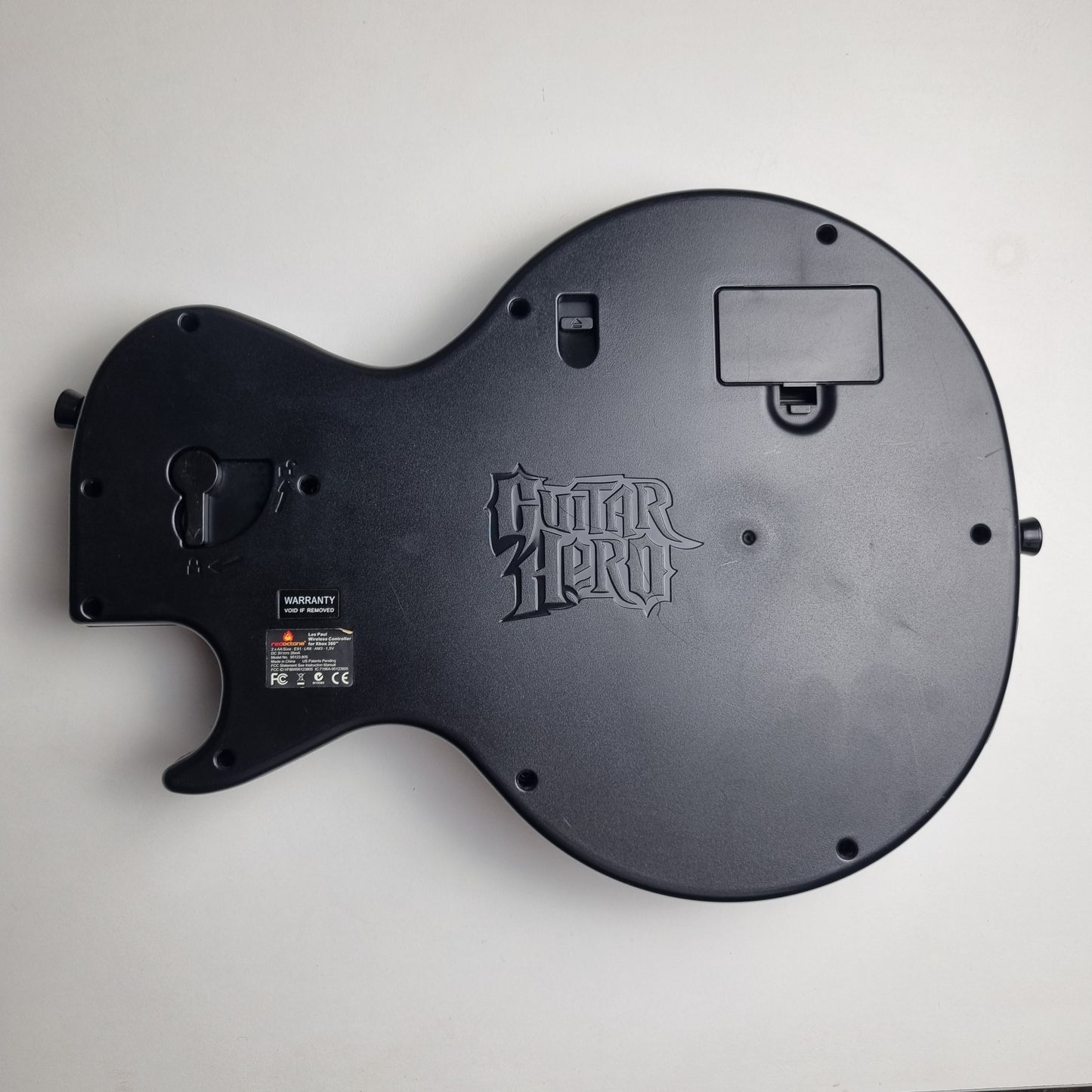 Back of a official RedOctane Xbox 360 Gibson Les Paul black guitar controller on a white background.