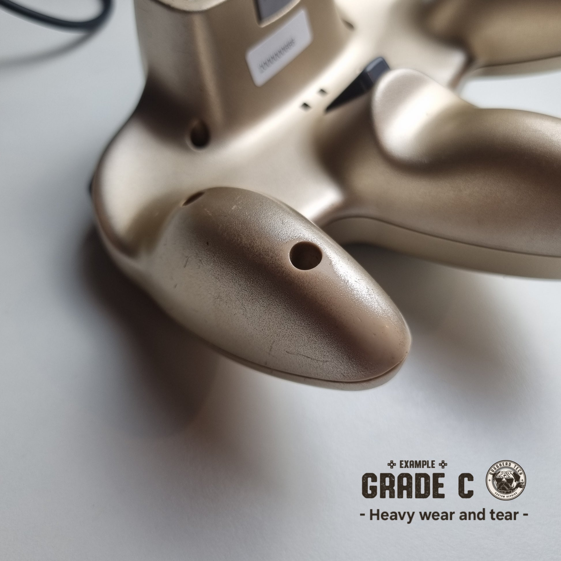 Close-up of the back part of a refurbished modified gold Nintendo 64 controller, showing significant wear and tear. The text reads 'Example Grade C: Heavy wear and tear'.