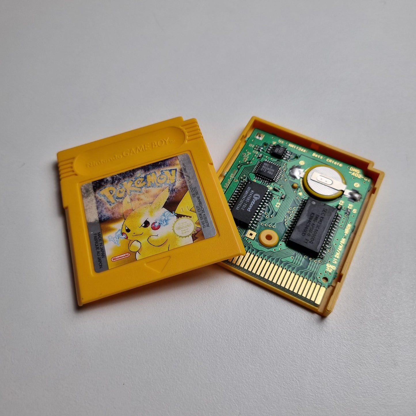 'Pokémon: Yellow Version' video game cartridge for Game Boy showing the character Pikachu. The cartridge is open, showing the PCB and replacement battery.