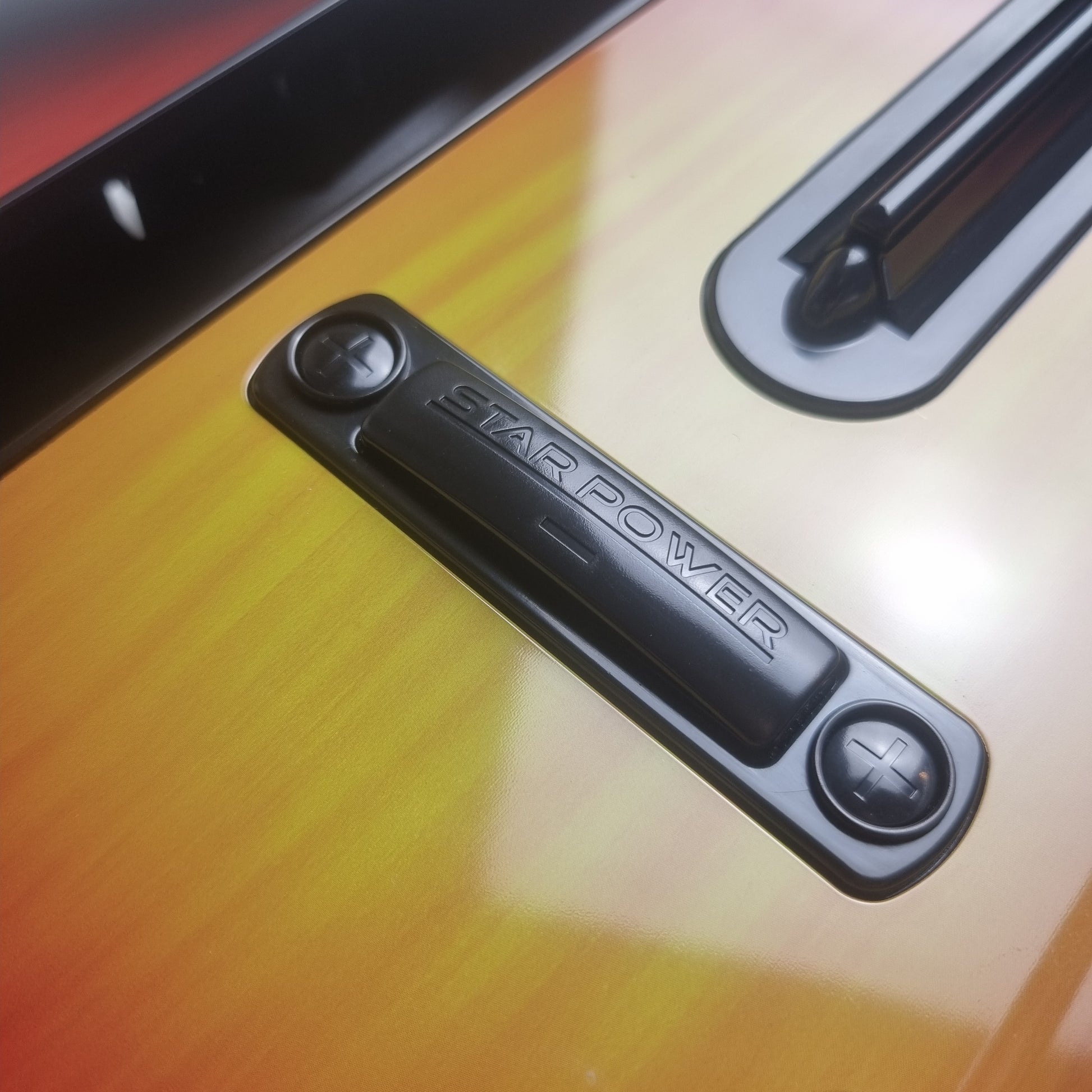 Close-up of the 'Star Power' button on a official RedOctane Nintendo Wii sunburst guitar controller.