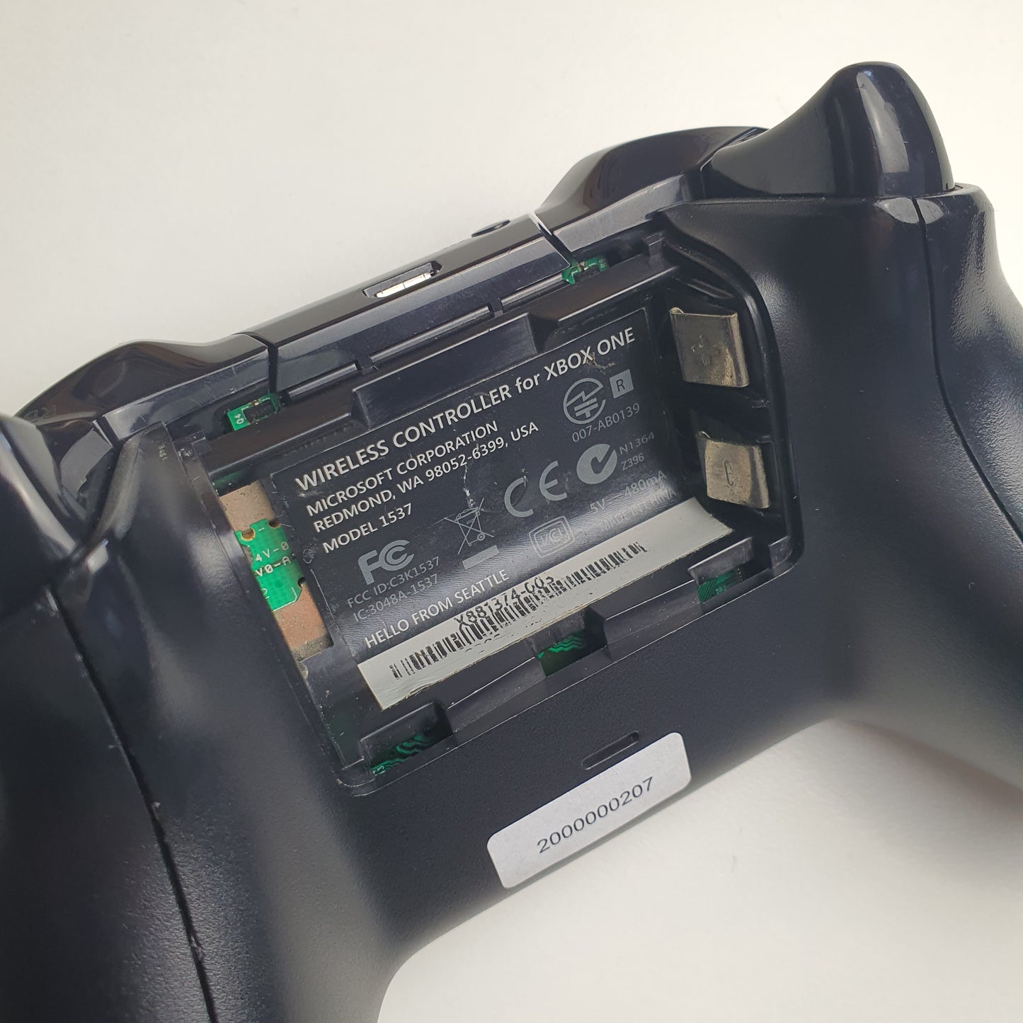 Close-up of a Xbox One controller with battery compartment open on a white background