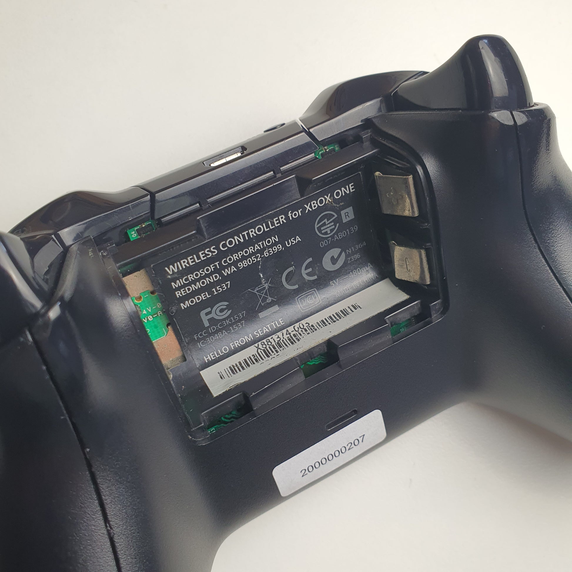 Close-up of a Xbox One controller with battery compartment open on a white background