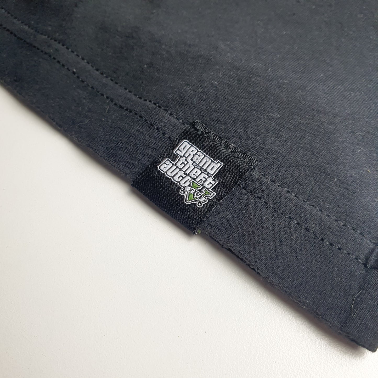 Close-up of black fabric with a GTA 5 label on a light grey background