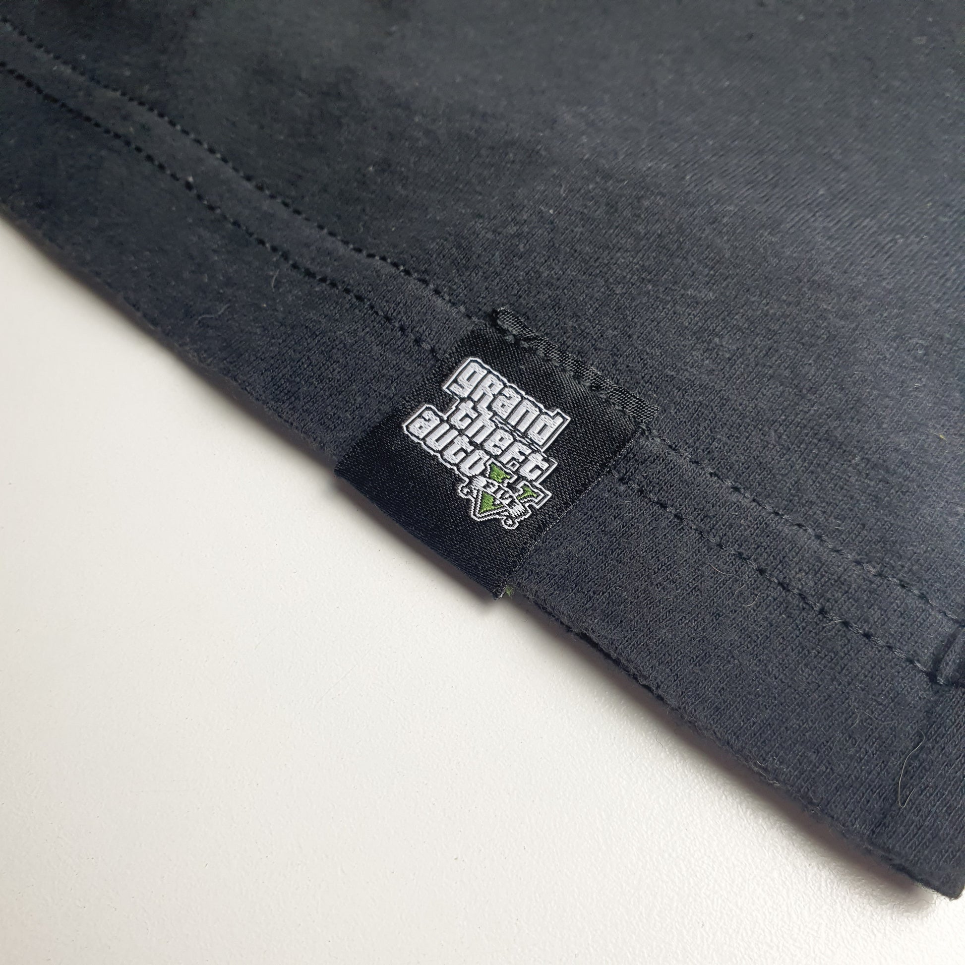 Close-up of black fabric with a GTA 5 label on a light grey background