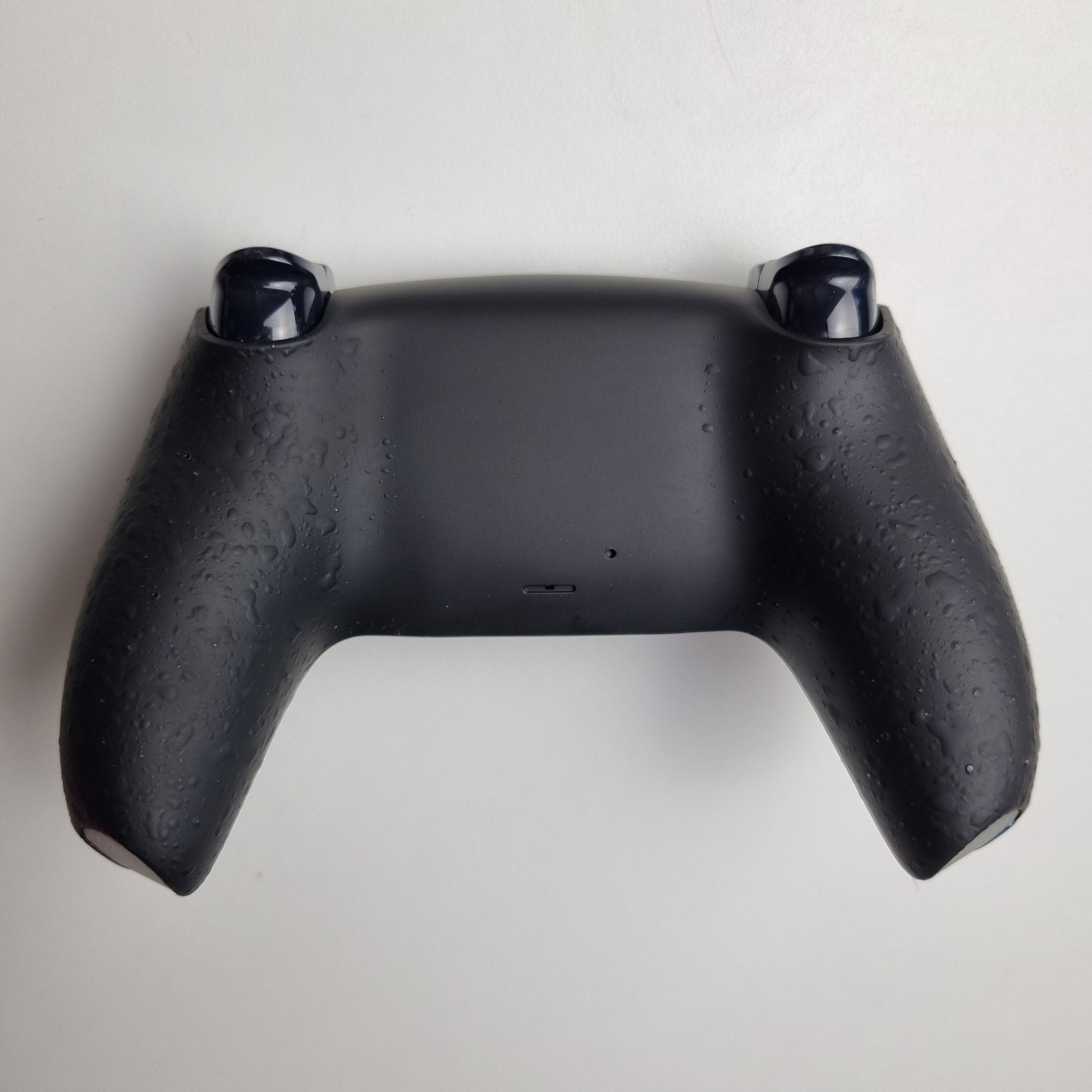 Black textured back of a custom PS5 controller built by Dogghead Tech on a white background.