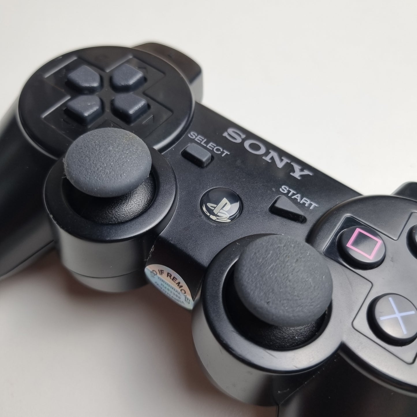 Close-up of a official Sony PlayStation PS3 SIXAXIS black wireless controller on a white background.