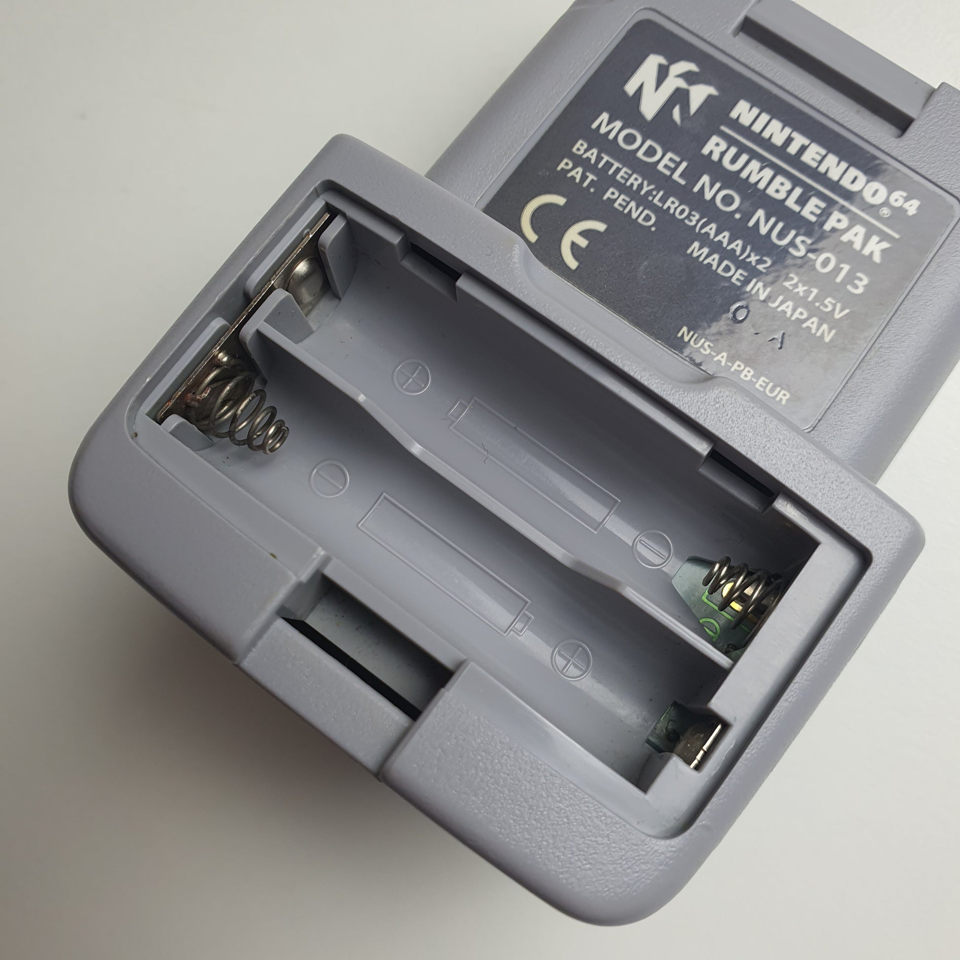 Close-up of the battery compartment of a Nintendo 64 N64 rumble pak on a white background