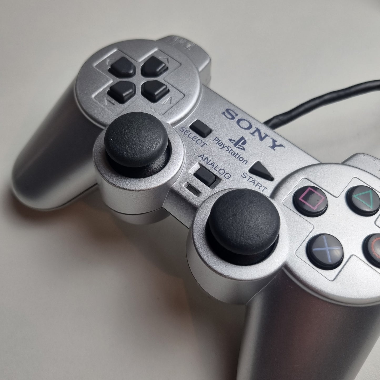 Close-up of the analog sticks of a refurbished official silver Sony PlayStation 2 wired controller.