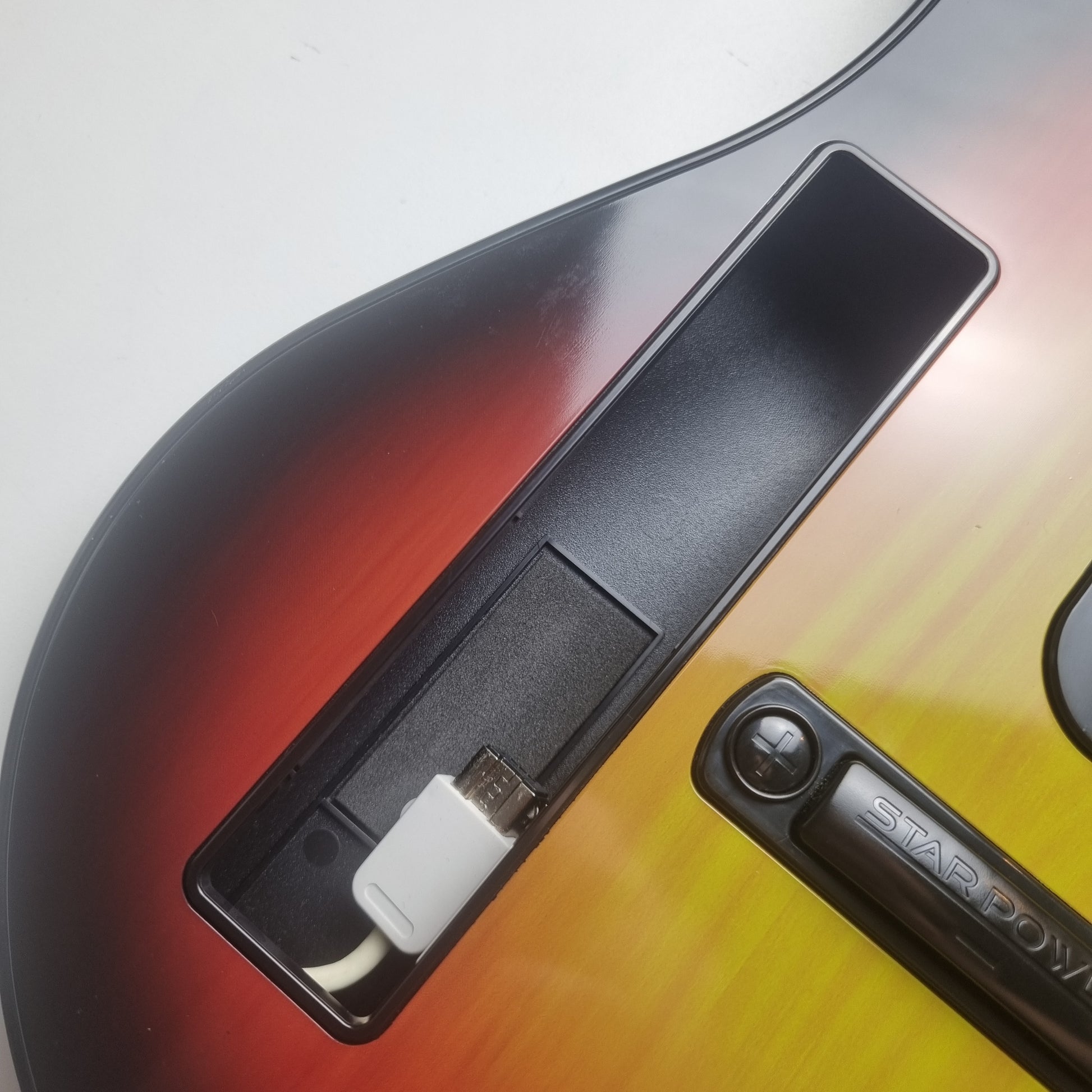 Close-up of the Wii remote slot on a official RedOctane Nintendo Wii sunburst guitar controller on a white background.