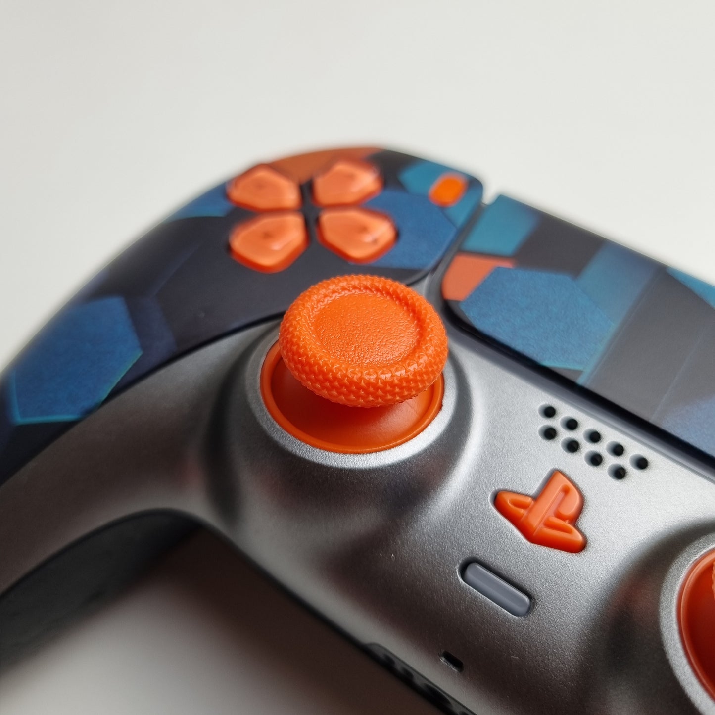 Close-up of the analog stick of a custom orange, teal & black Sony PlayStation 5 PS5 wireless DualSense controller built by Dogghead Tech on a white background.