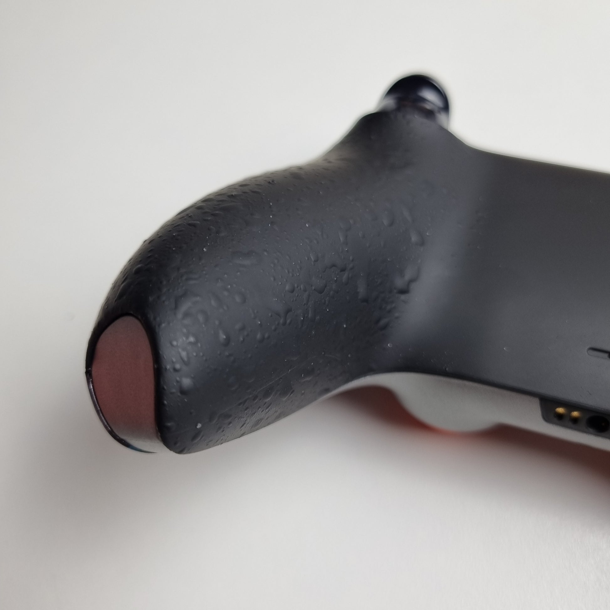 Close-up of the black textured back of a custom PS5 controller built by Dogghead Tech on a white background.