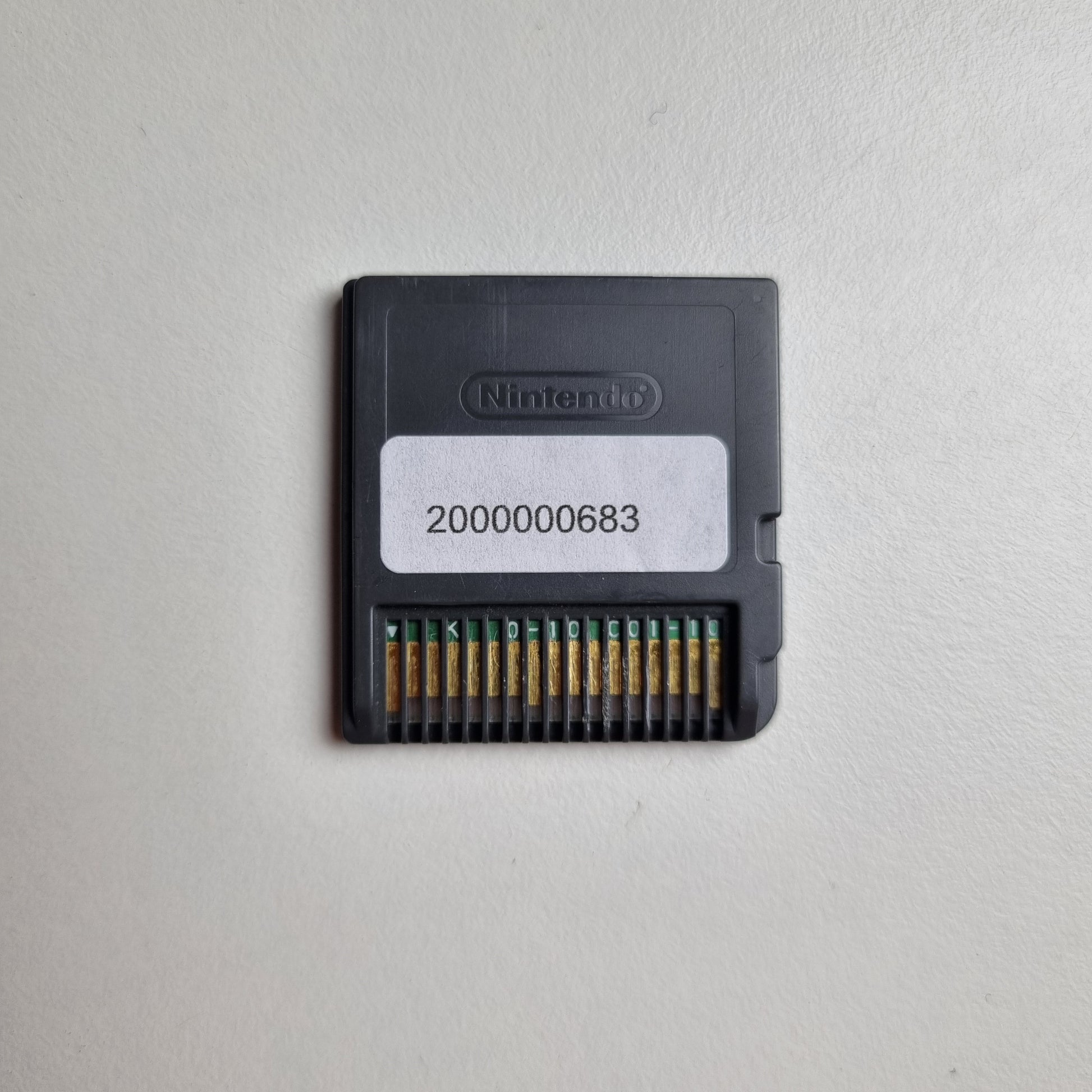 Back of a Nintendo DS game cartridge showing an asset tag, on a light grey background