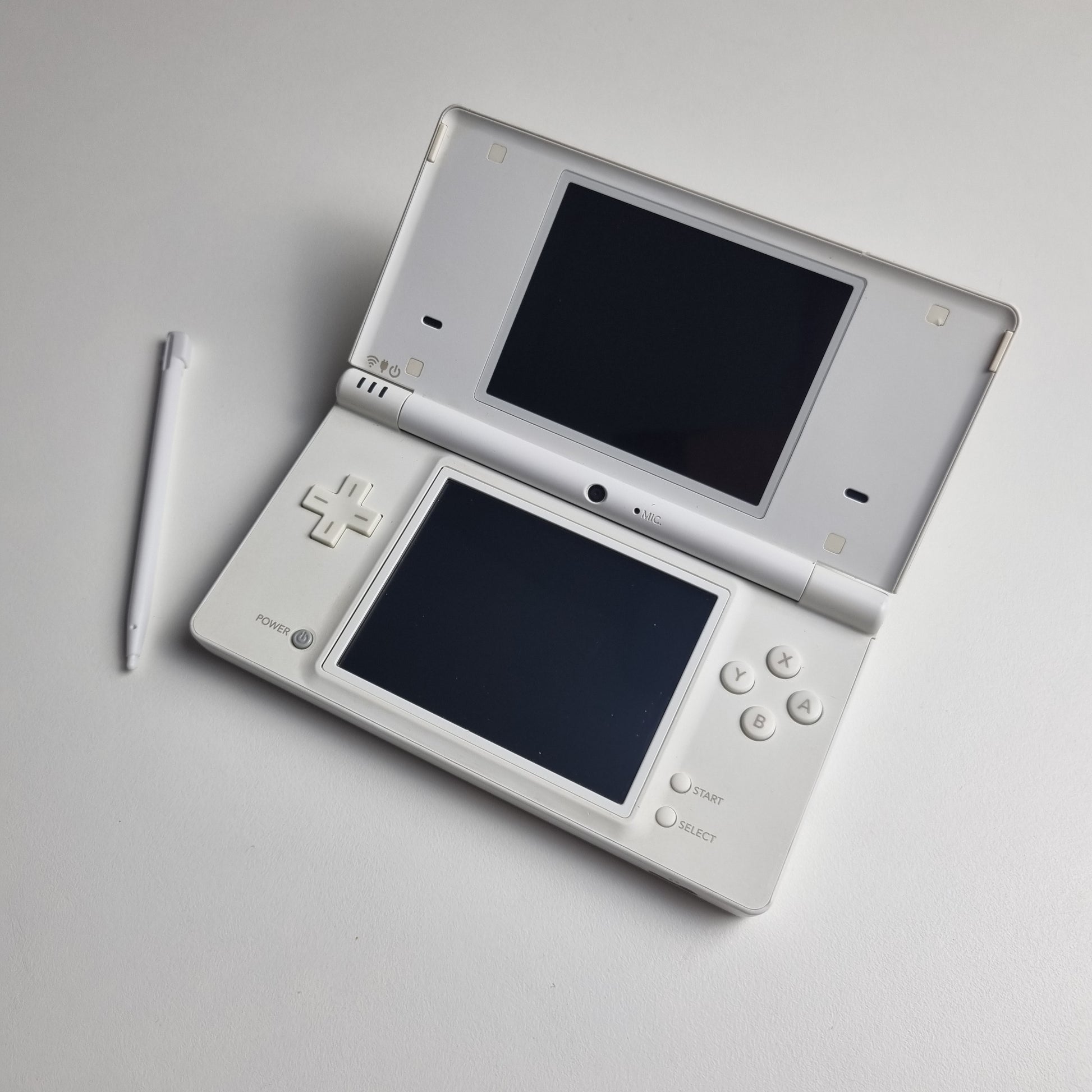 White Nintendo DSi handheld console with stylus, on a light grey background.