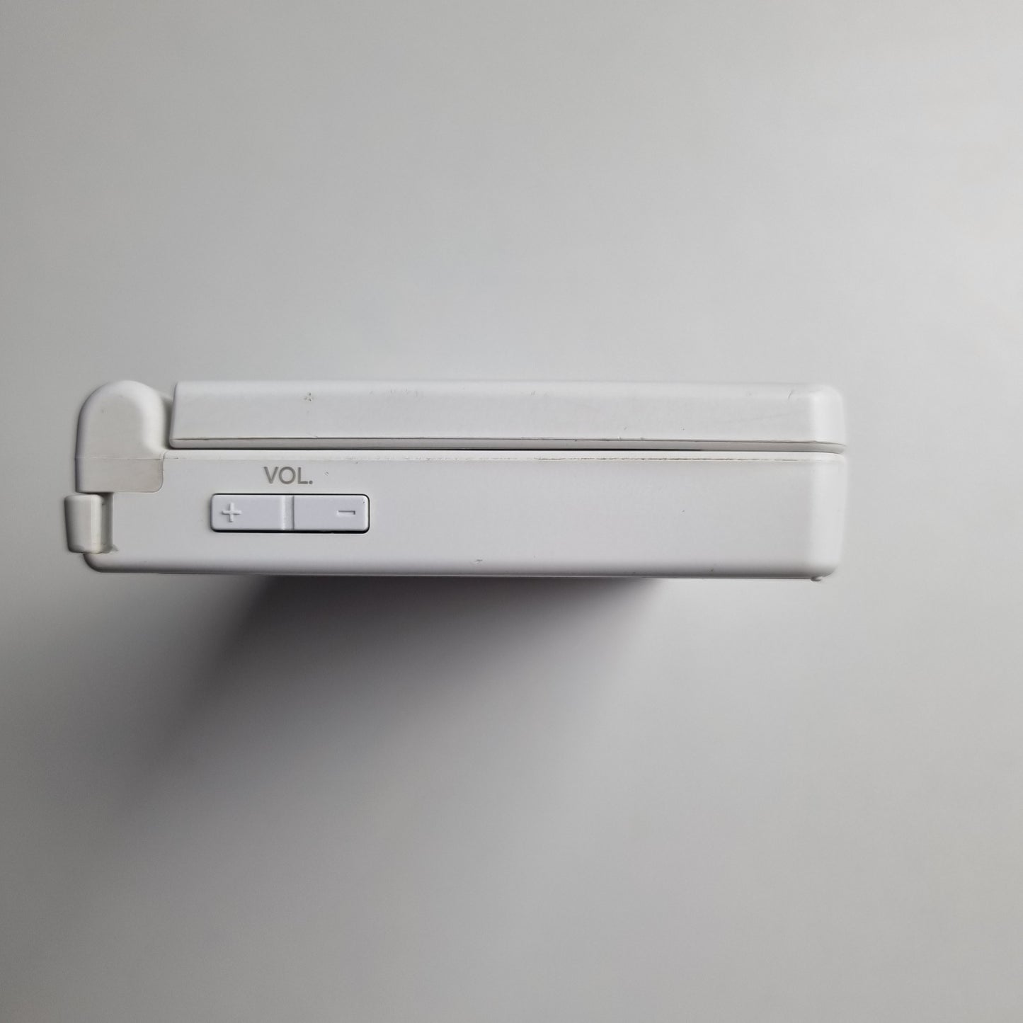 Side of a white Nintendo DSi handheld console on a light grey background.