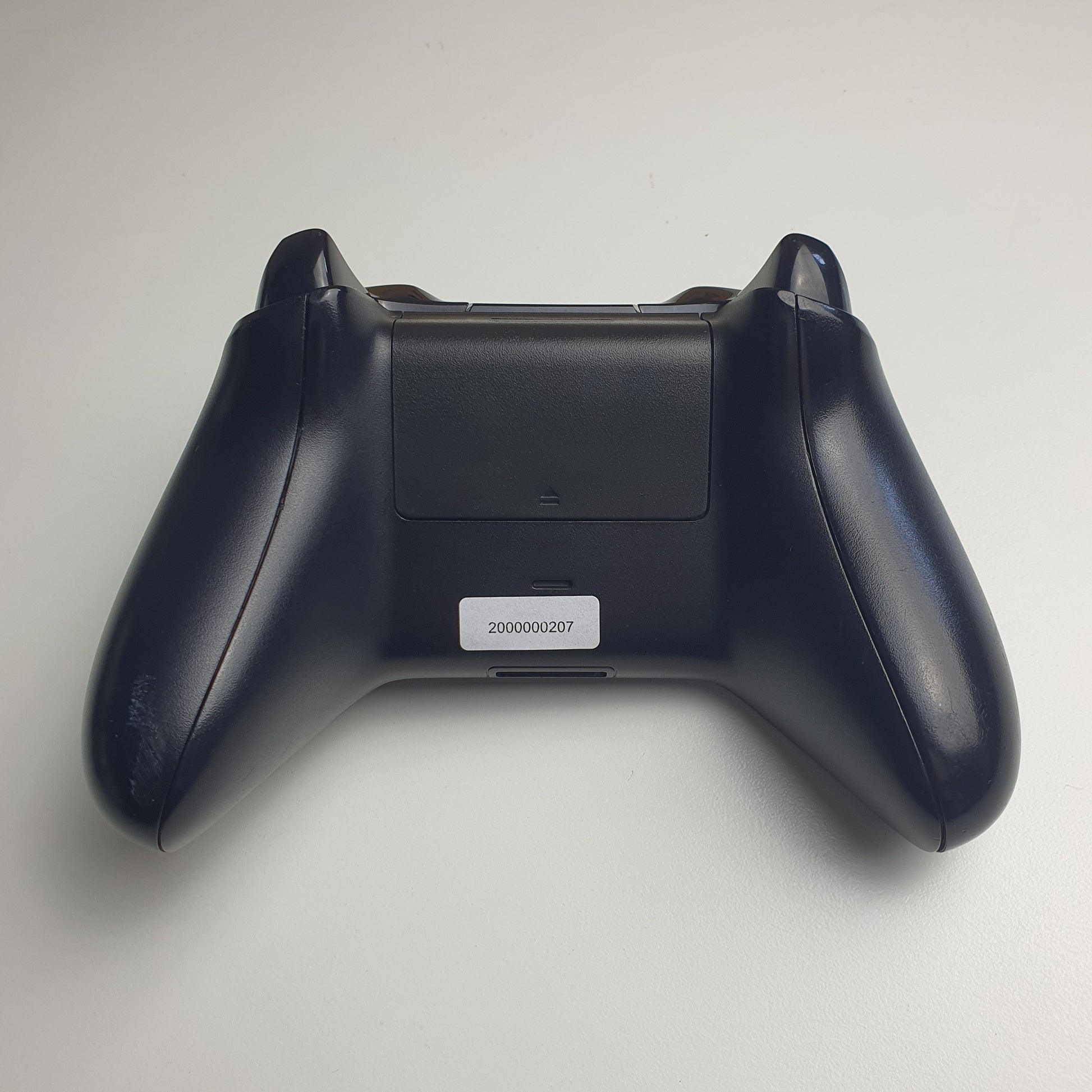 The back of a black Xbox One controller on a white background