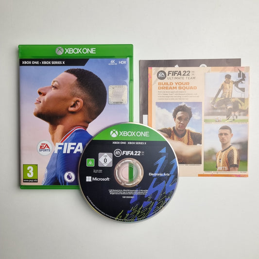Xbox One & Series X|S game case, disc and inserts for 'FIFA 22' on a light grey background