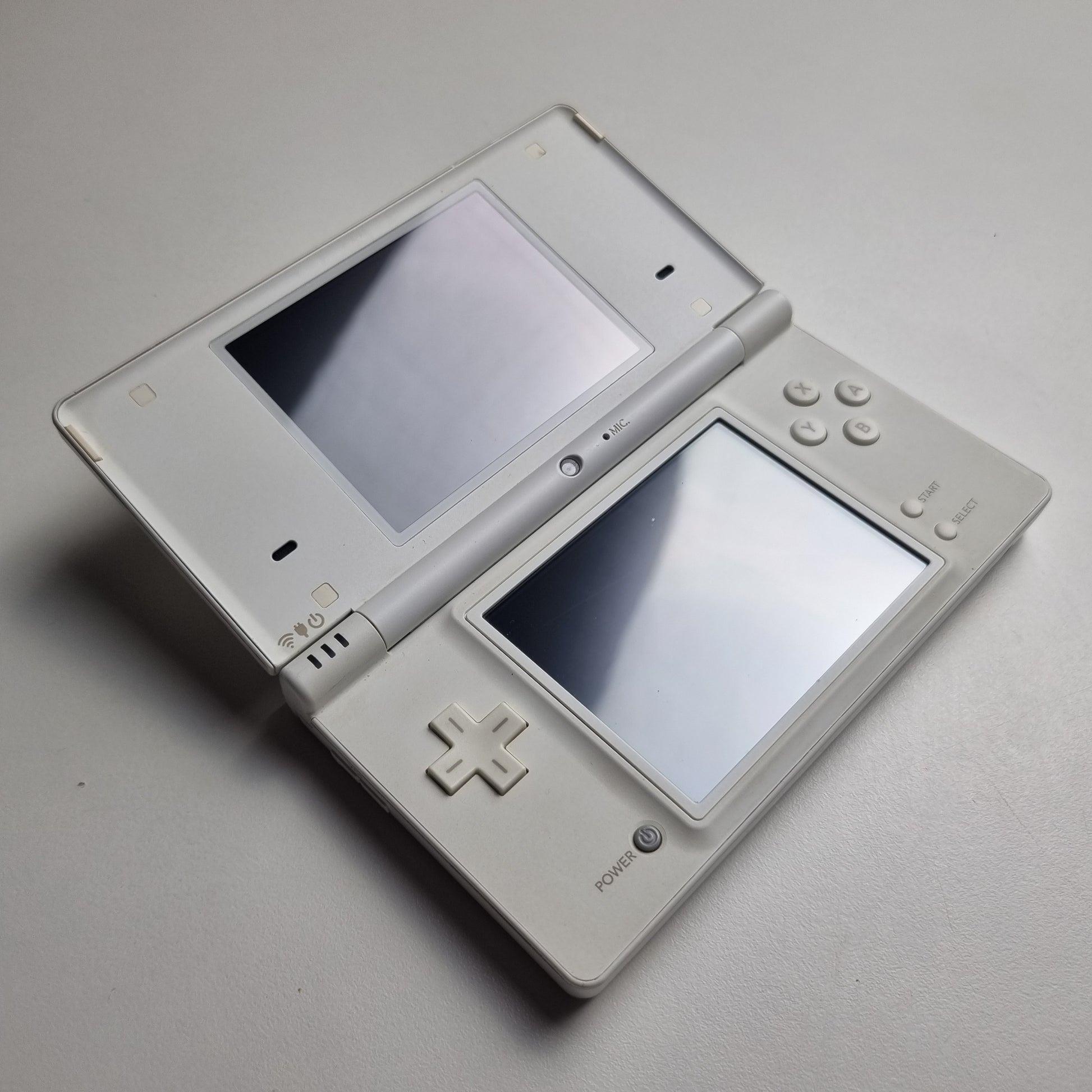 White Nintendo DSi handheld console showing the surfaces of the screens, on a light grey background.