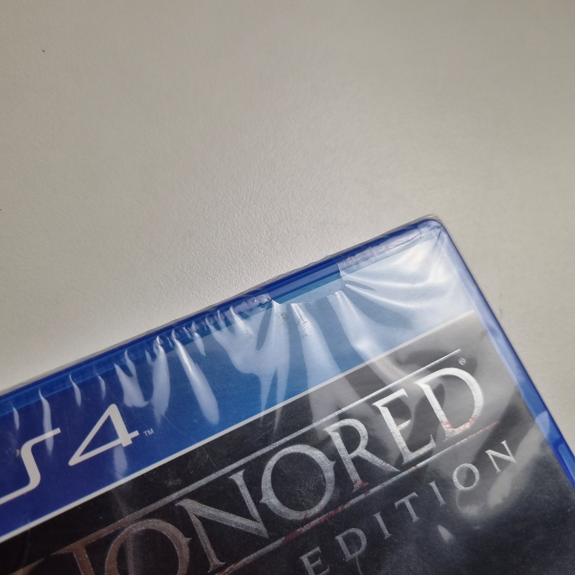 Close-up of a brand new official Sony PlayStation 4 game titled 'Dishonored: Definitive Edition' on a  gray background