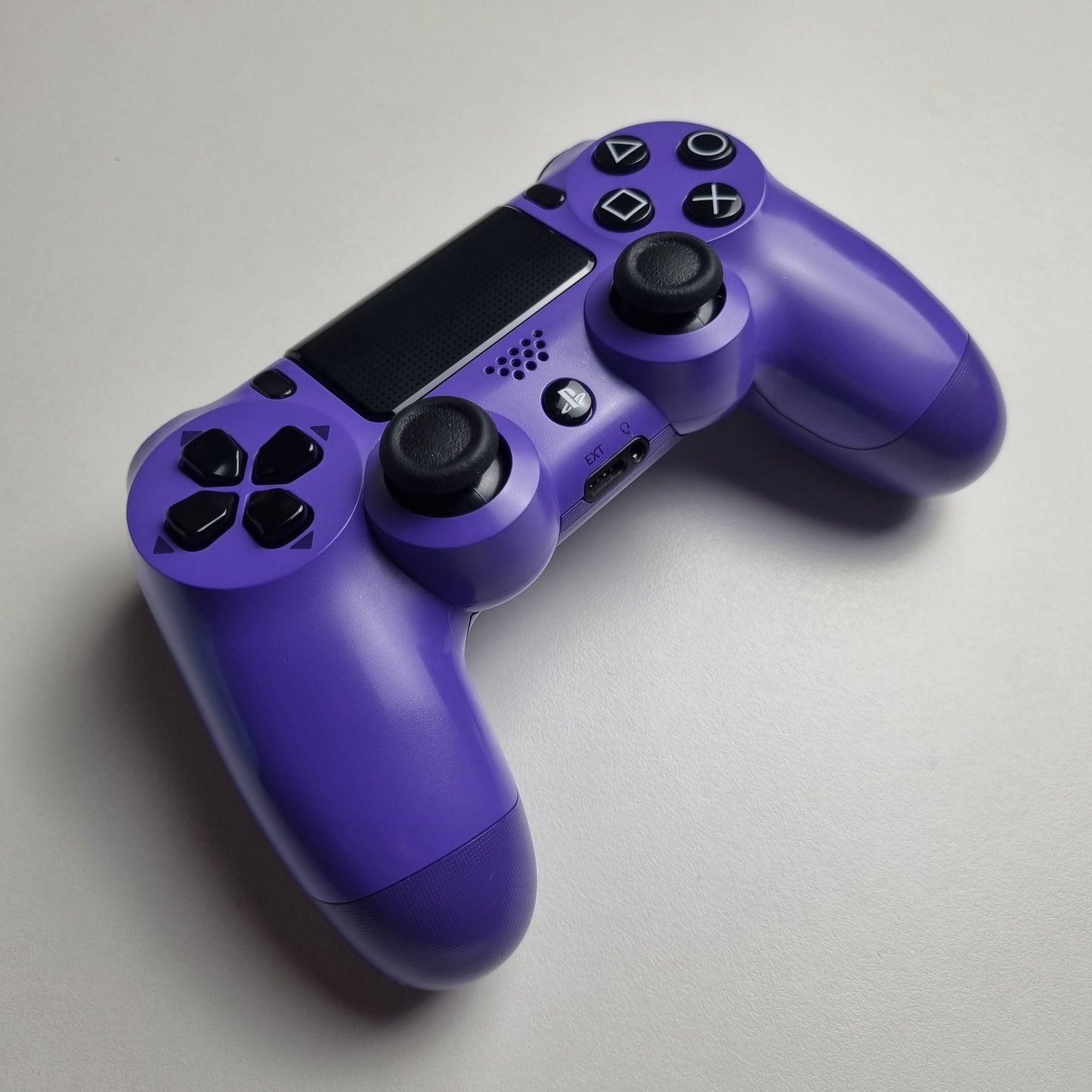 Electric purple official Sony PlayStation DualShock 4 refurbished gaming controller on a light gray background