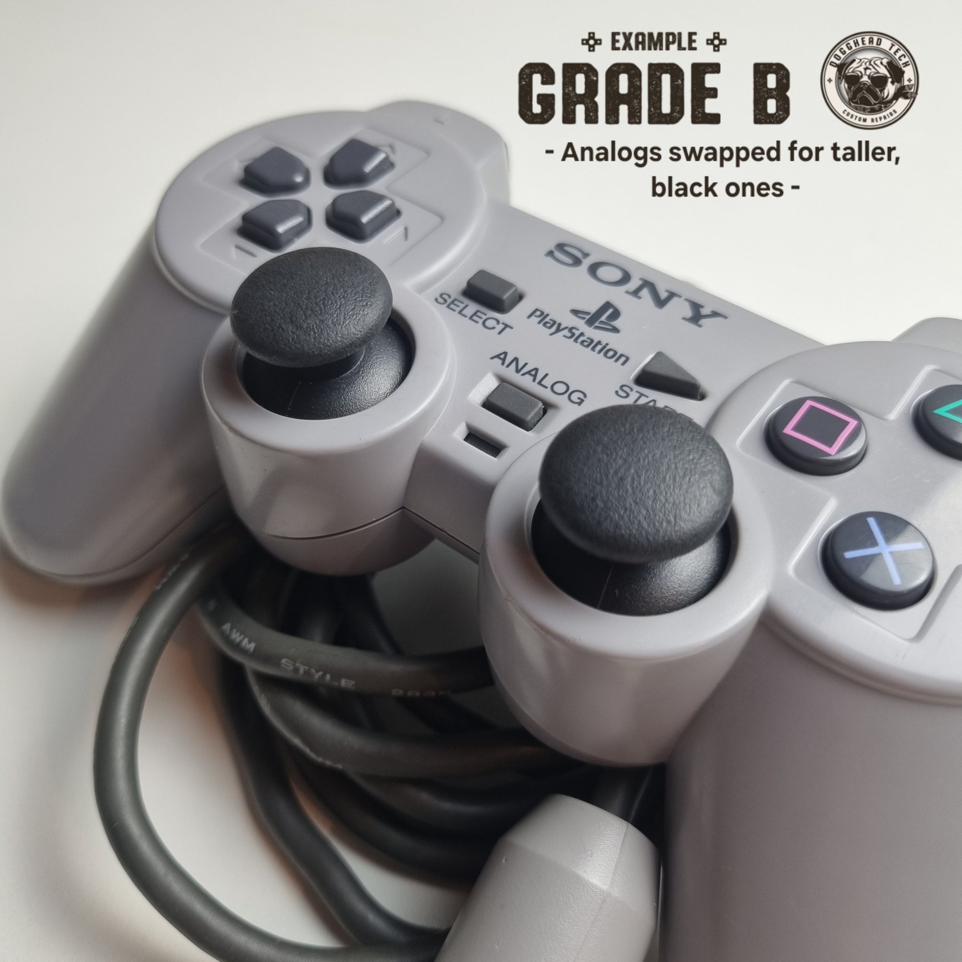 Close-up of a pair of replacement analog sticks, taller and black in colour, on a Refurbished official Sony PlayStation DualShock wired grey controller. The caption reads 'Example Grade B: Analogs swapped for taller, black ones' in the top corner.
