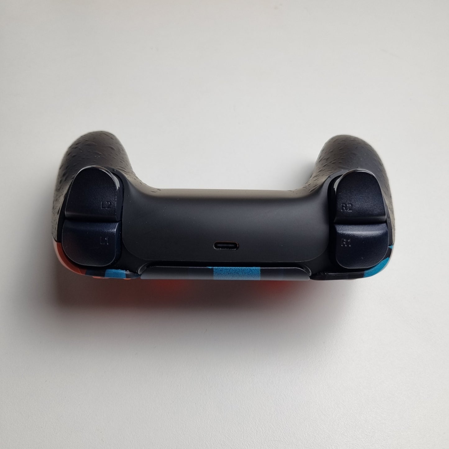 Black top of a custom PS5 controller built by Dogghead Tech on a white background.